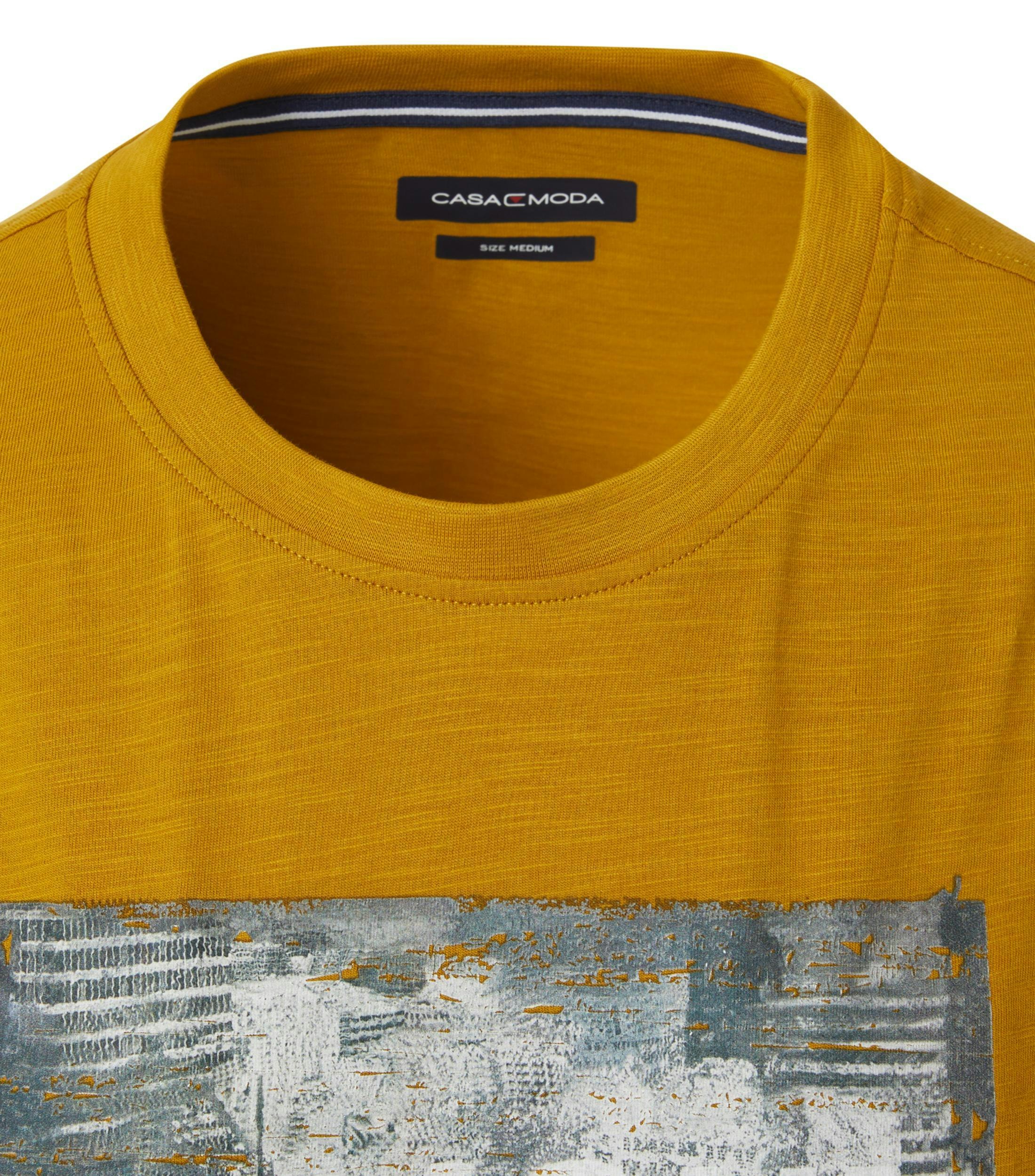 Das Model trägt ein TShirt im uni Muster in der Farbe Senfgelb