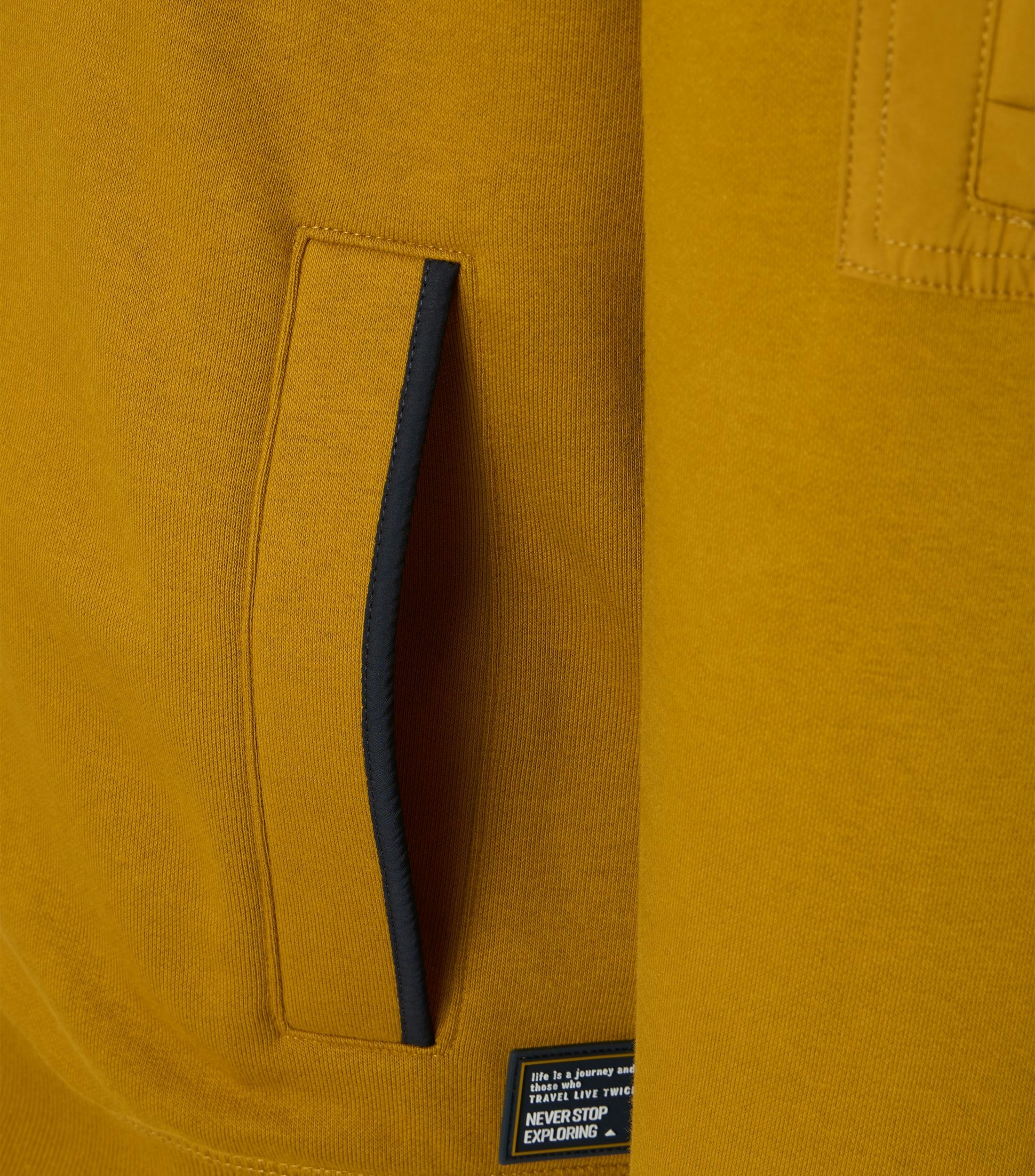 Das Model trägt ein Sweatshirt im uni Muster in der Farbe Senfgelb