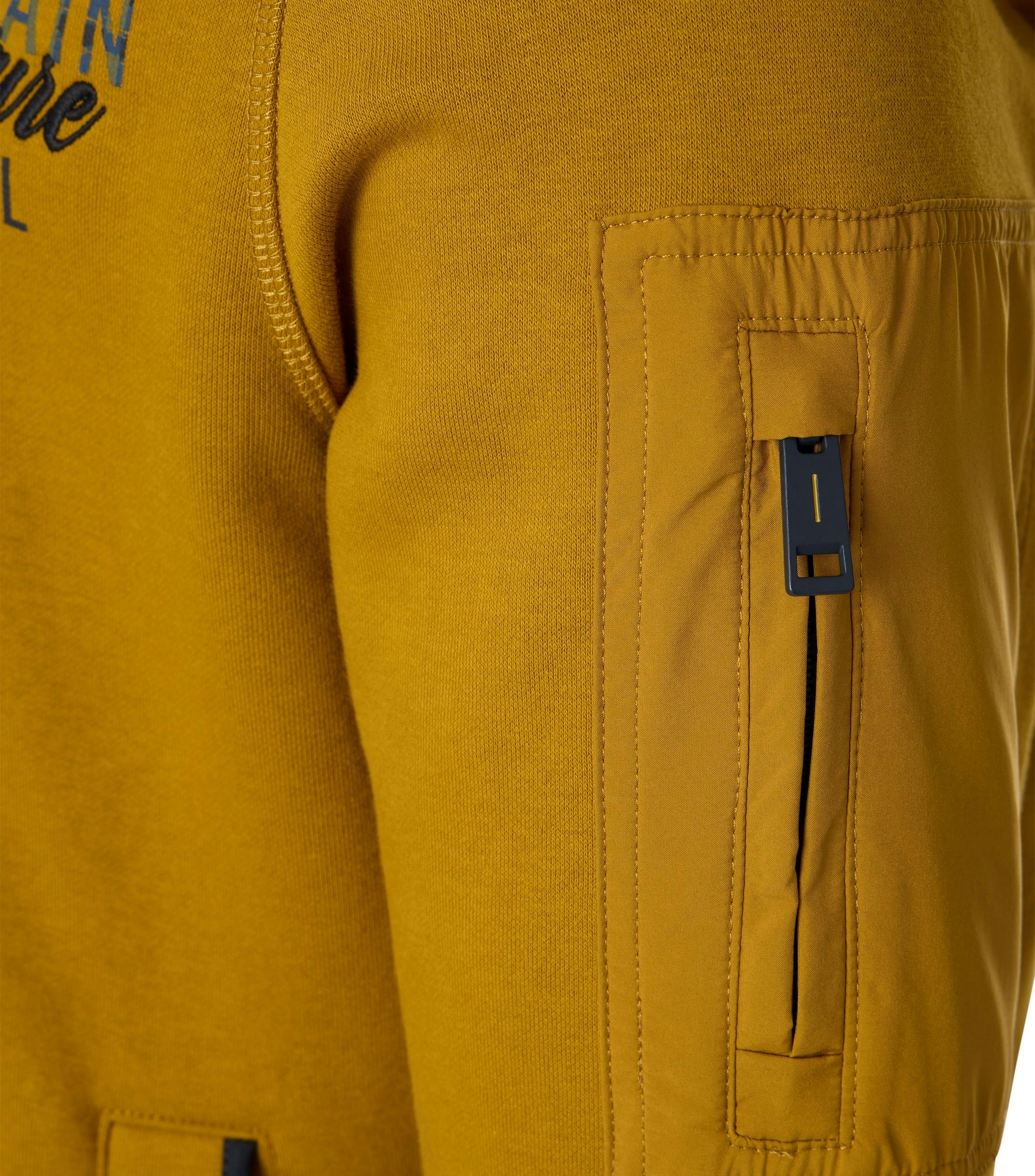 Das Model trägt ein Sweatshirt im uni Muster in der Farbe Senfgelb