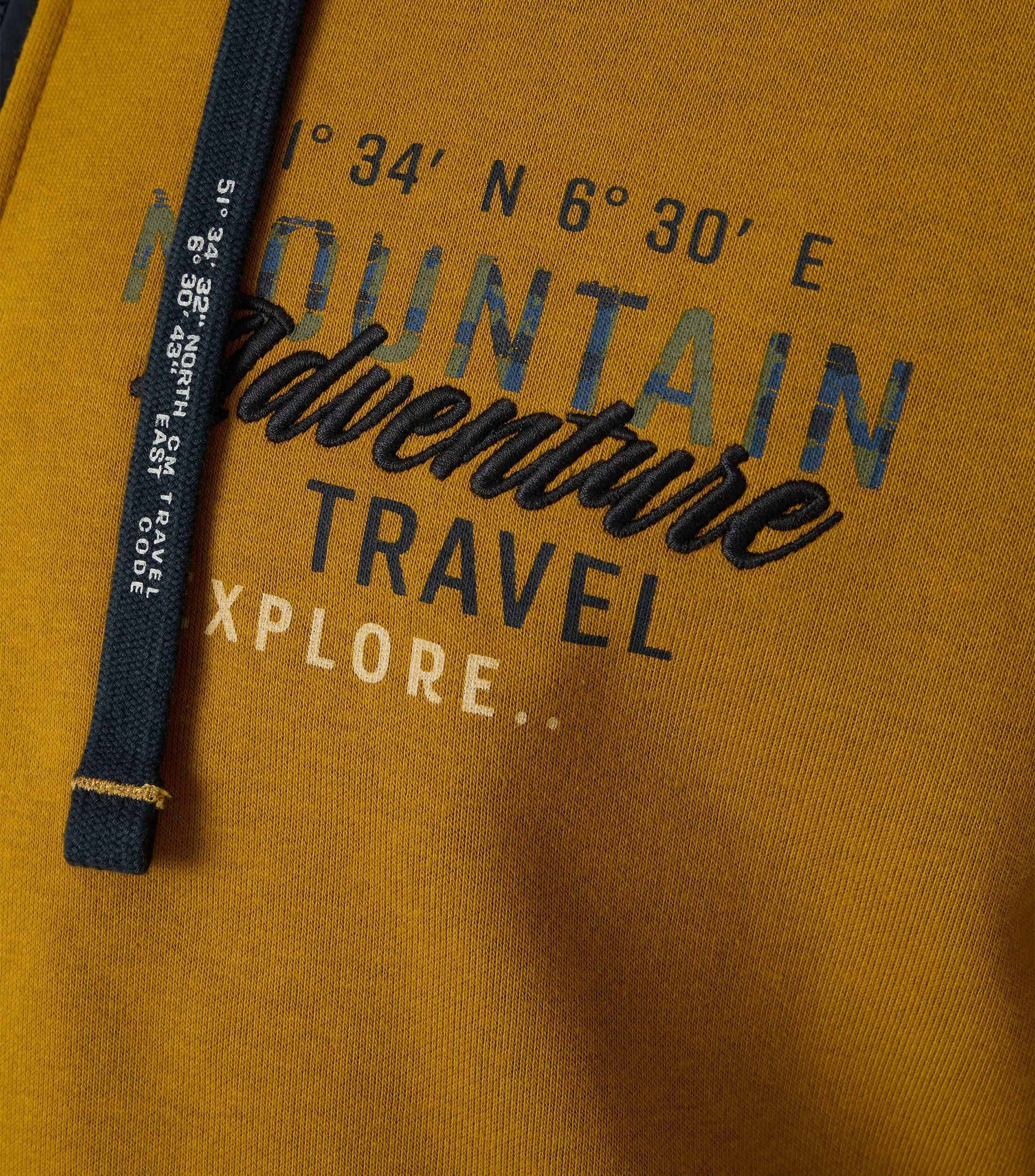 Das Model trägt ein Sweatshirt im uni Muster in der Farbe Senfgelb