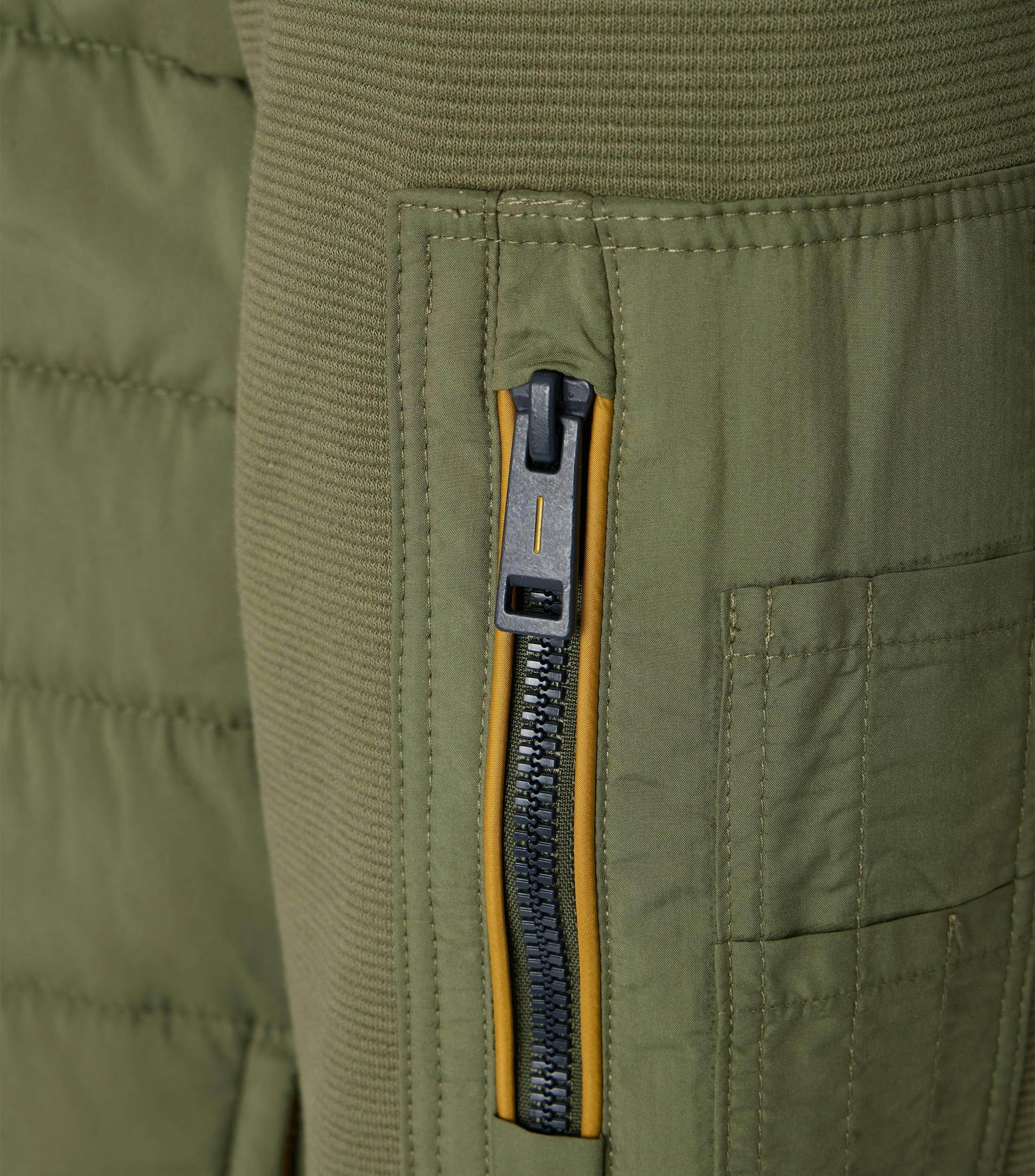 Das Model trägt eine Sweatjacke im uni Muster in der Farbe Grün