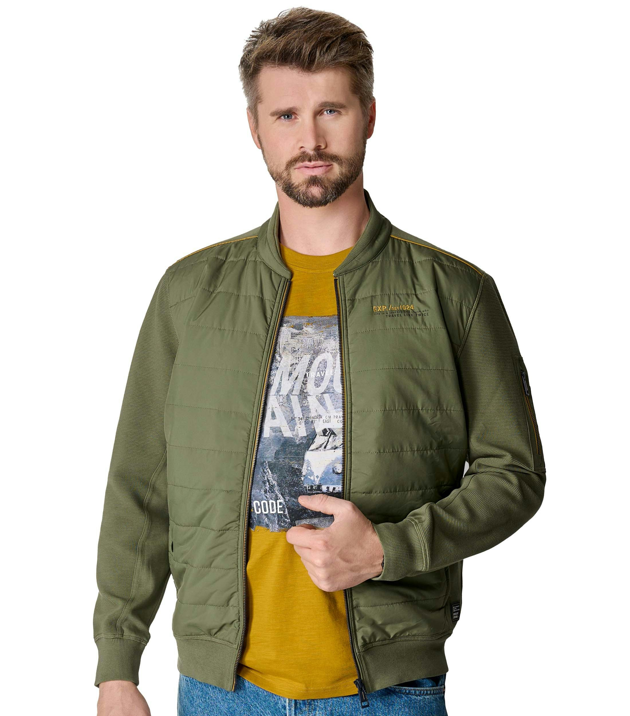 Das Model trägt eine Sweatjacke im uni Muster in der Farbe Grün