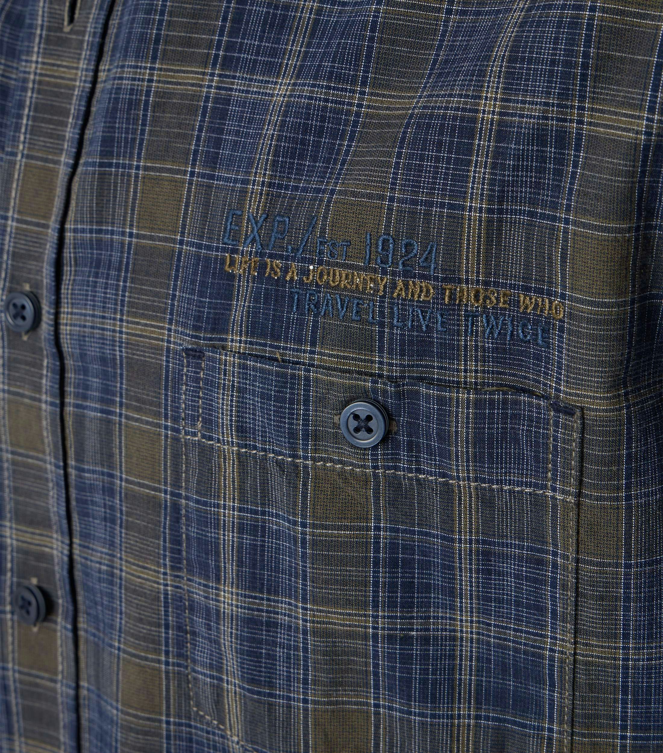 Das Model trägt ein Freizeithemd im kariert Muster in der Farbe Blau