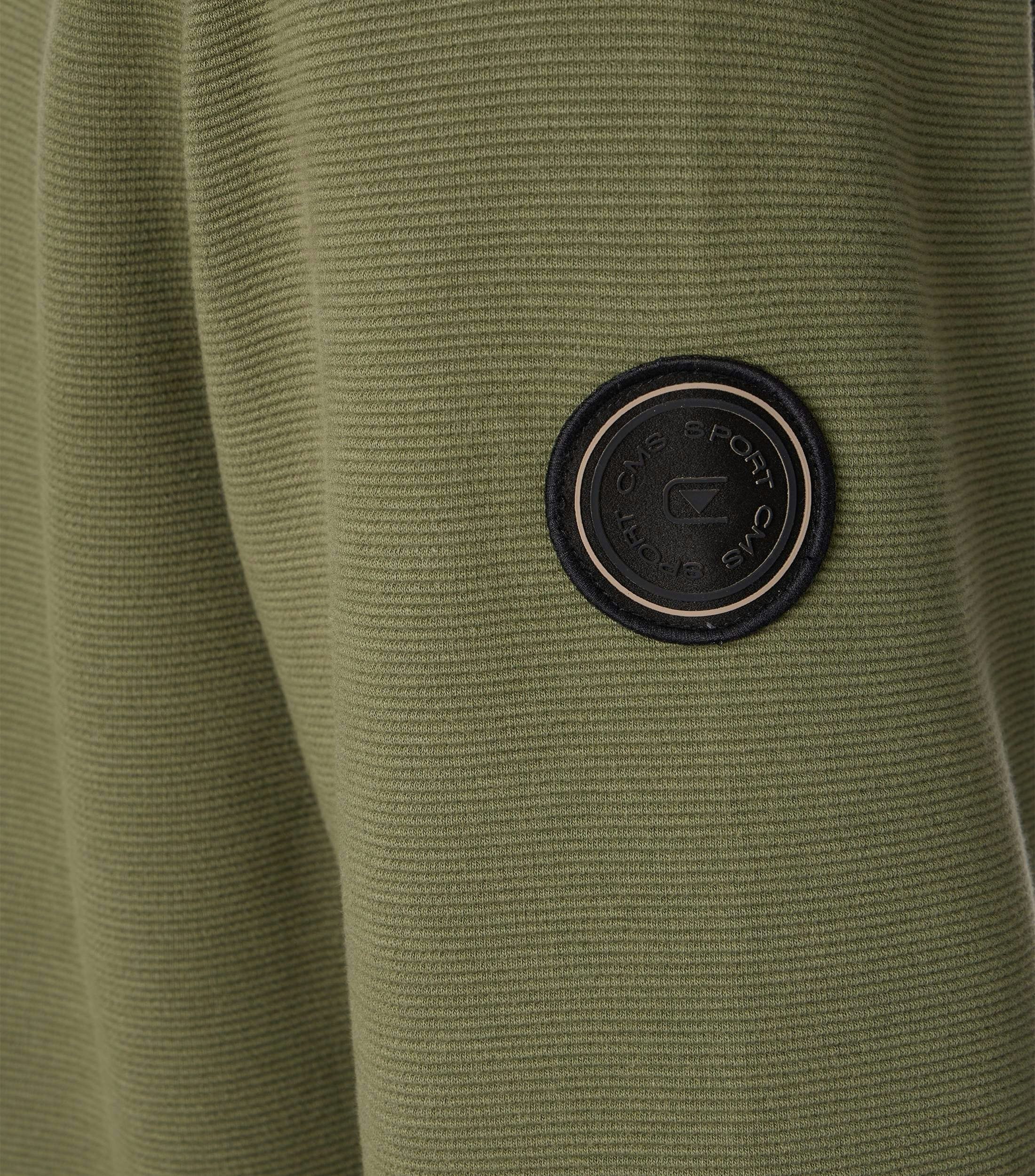 Das Model trägt ein Sweatshirt im uni Muster in der Farbe Grün