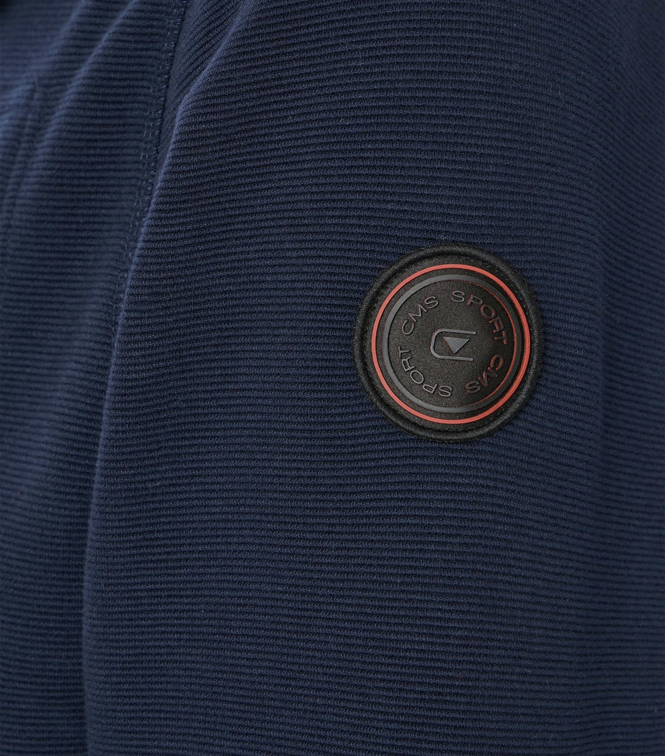 Das Model trägt eine Sweatjacke im uni Muster in der Farbe Blau