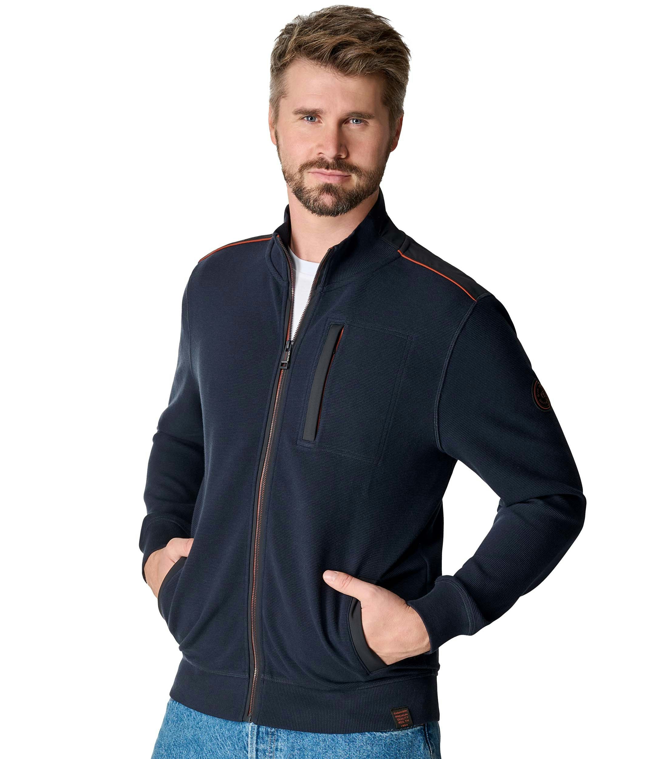 Das Model trägt eine Sweatjacke im uni Muster in der Farbe Blau