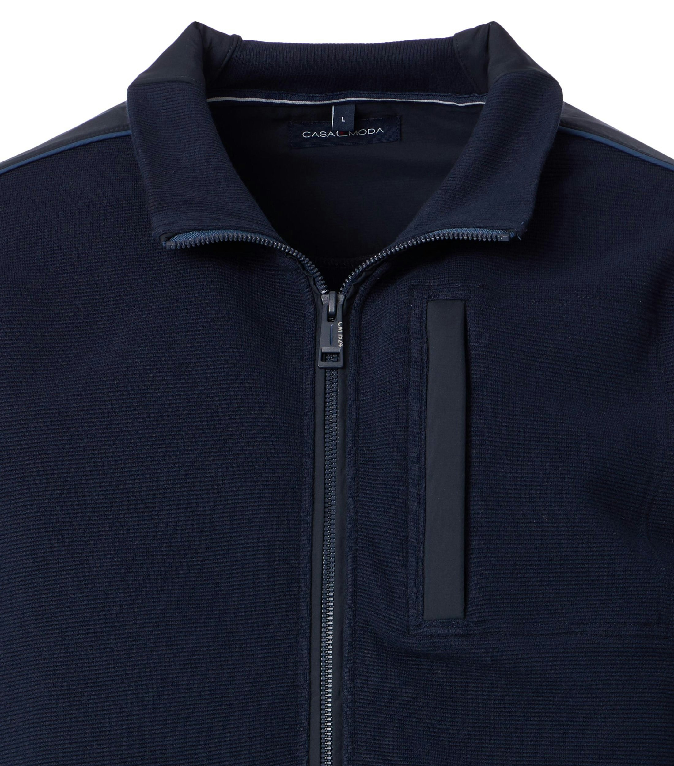 Das Model trägt eine Sweatjacke im uni Muster in der Farbe blau