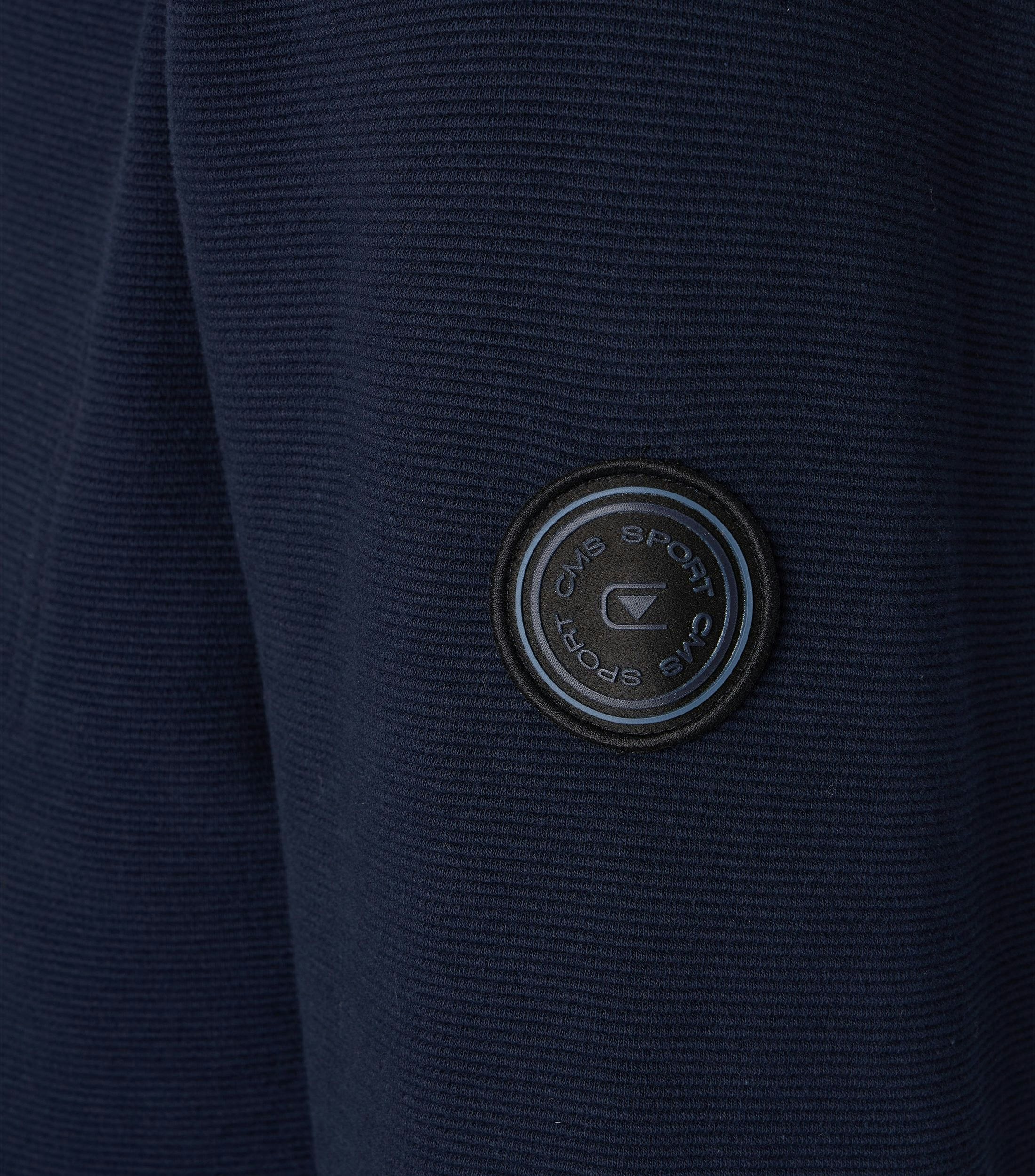 Das Model trägt eine Sweatjacke im uni Muster in der Farbe blau