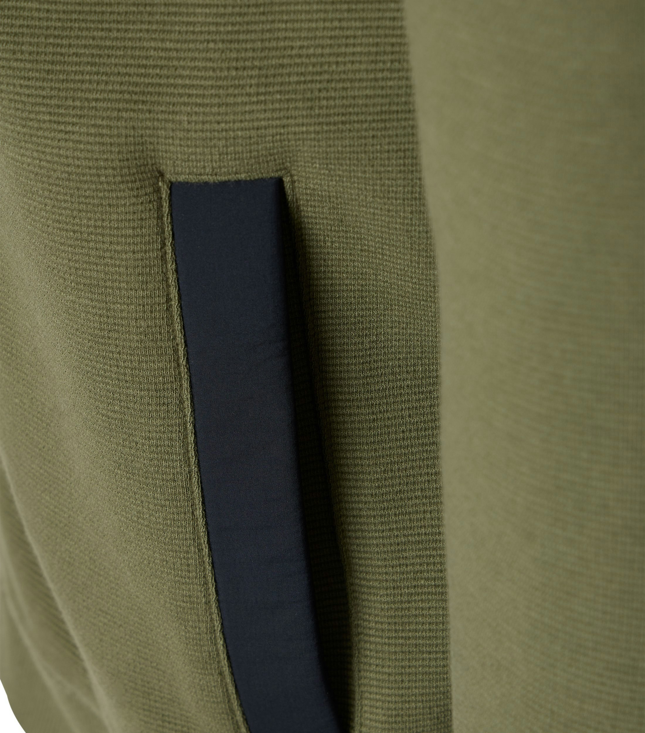 Das Model trägt eine Sweatjacke im uni Muster in der Farbe Grün