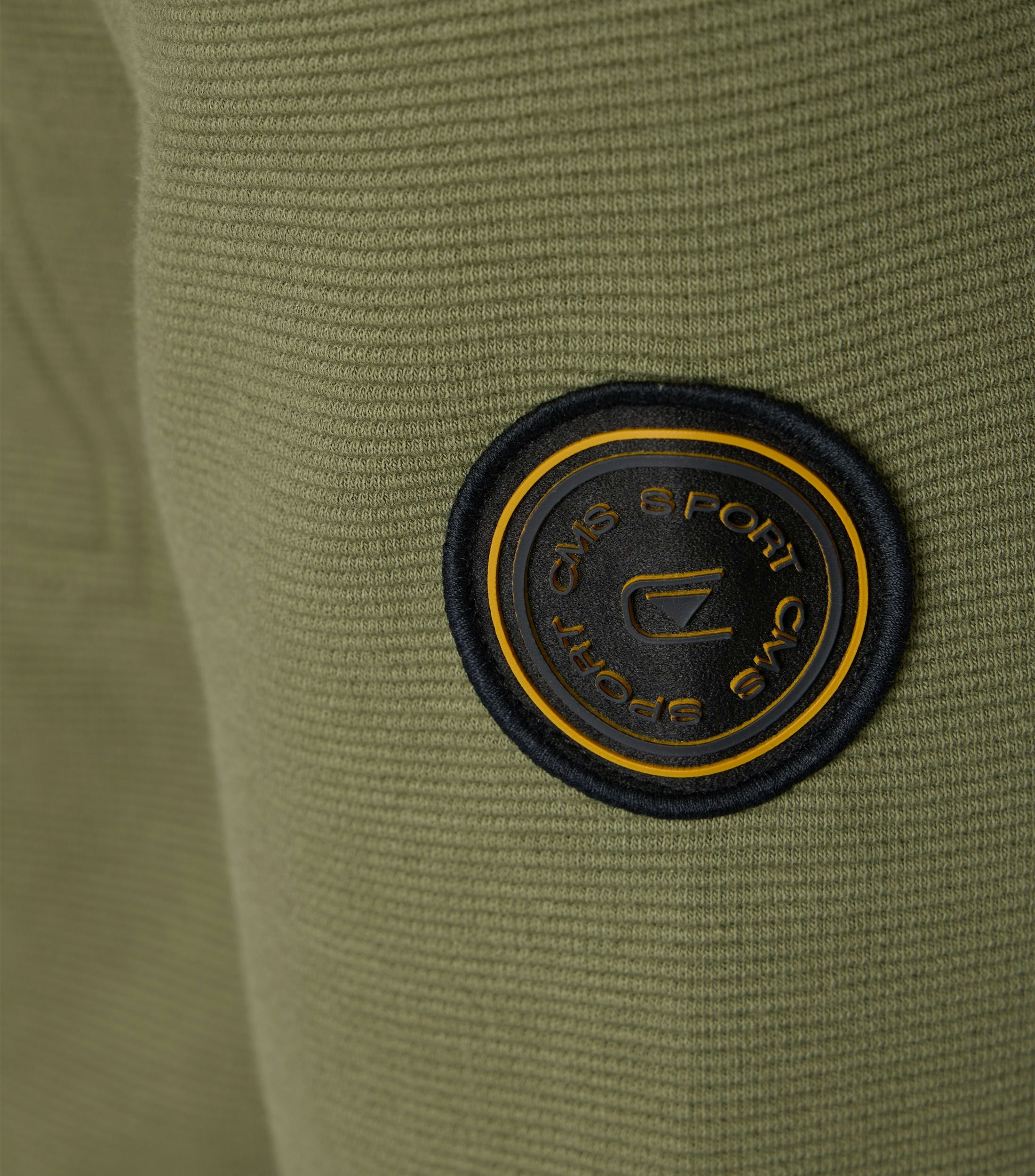 Das Model trägt eine Sweatjacke im uni Muster in der Farbe Grün