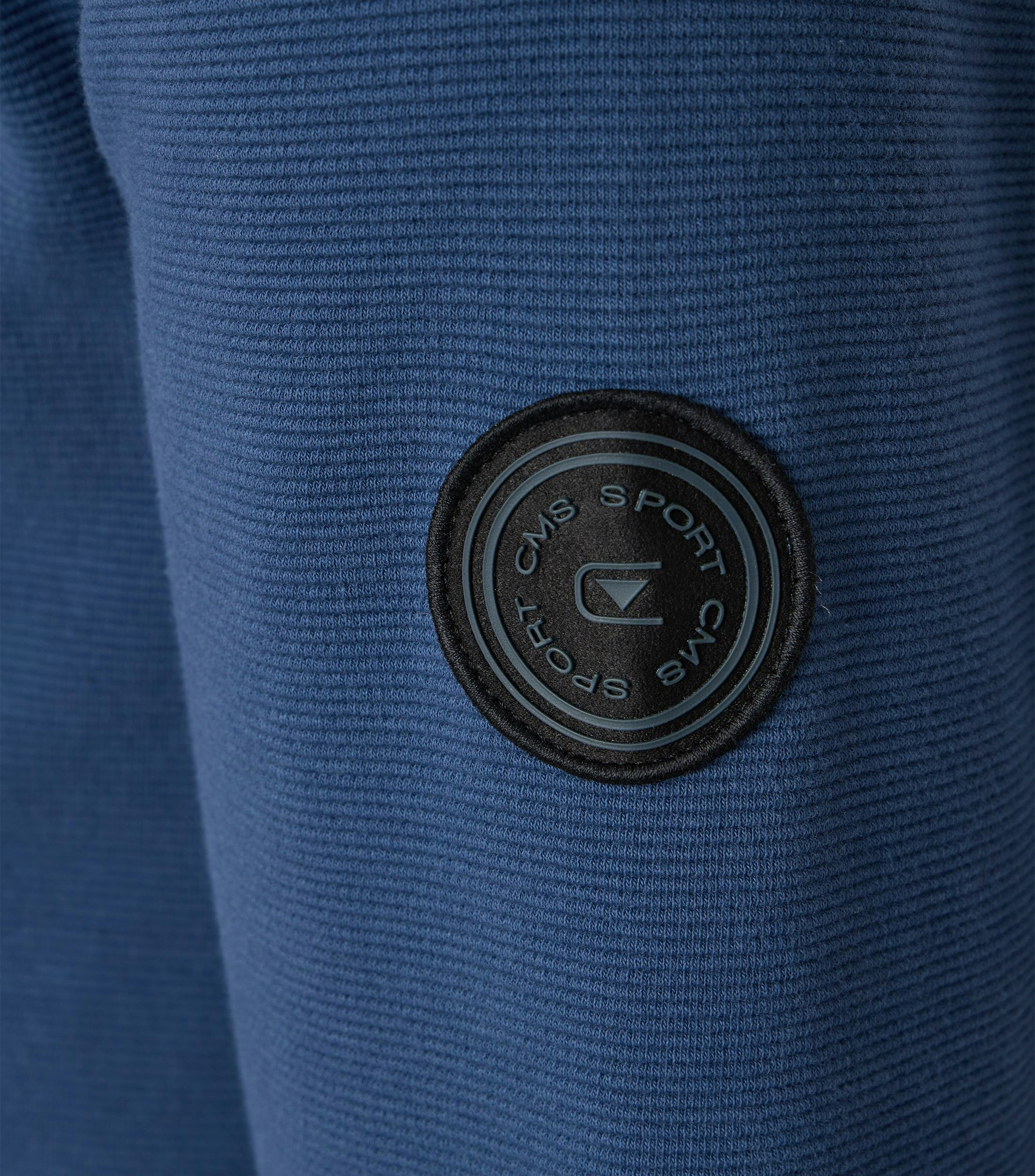 Das Model trägt eine Sweatjacke im uni Muster in der Farbe mittleres Dunkelblau