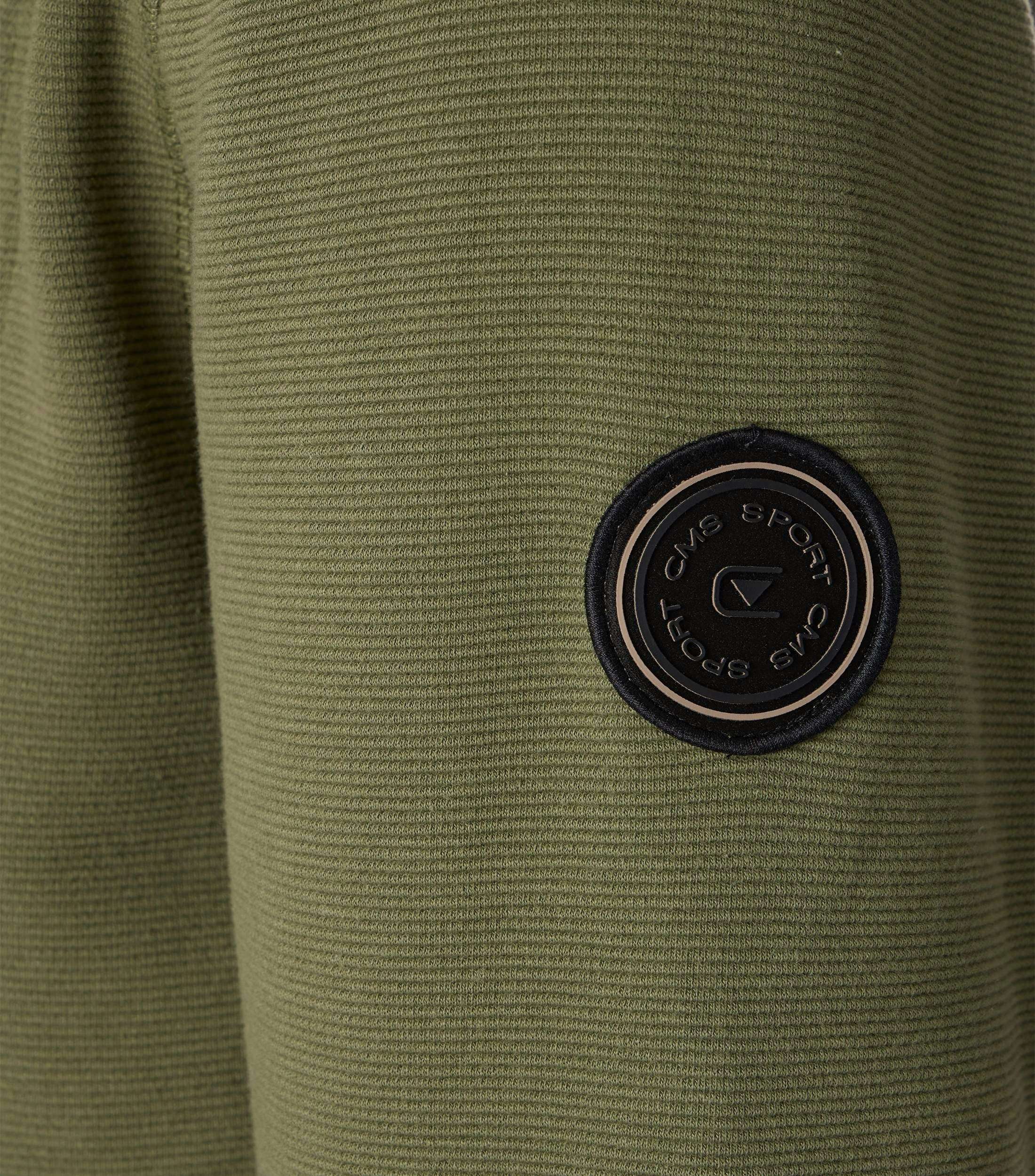 Das Model trägt eine Sweatjacke im uni Muster in der Farbe Dunkelgrün