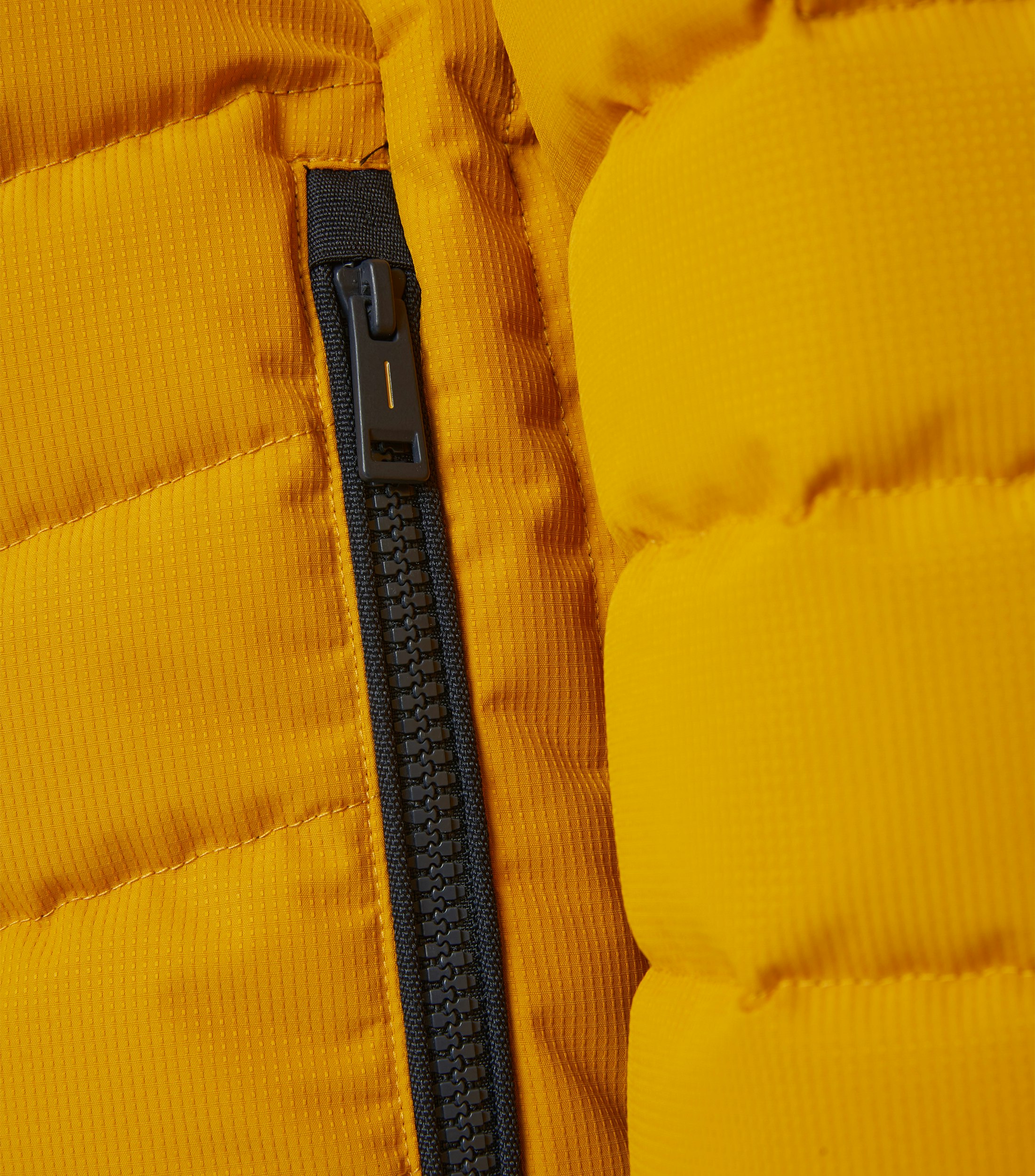 Das Model trägt eine Jacke im uni Muster in der Farbe Senfgelb