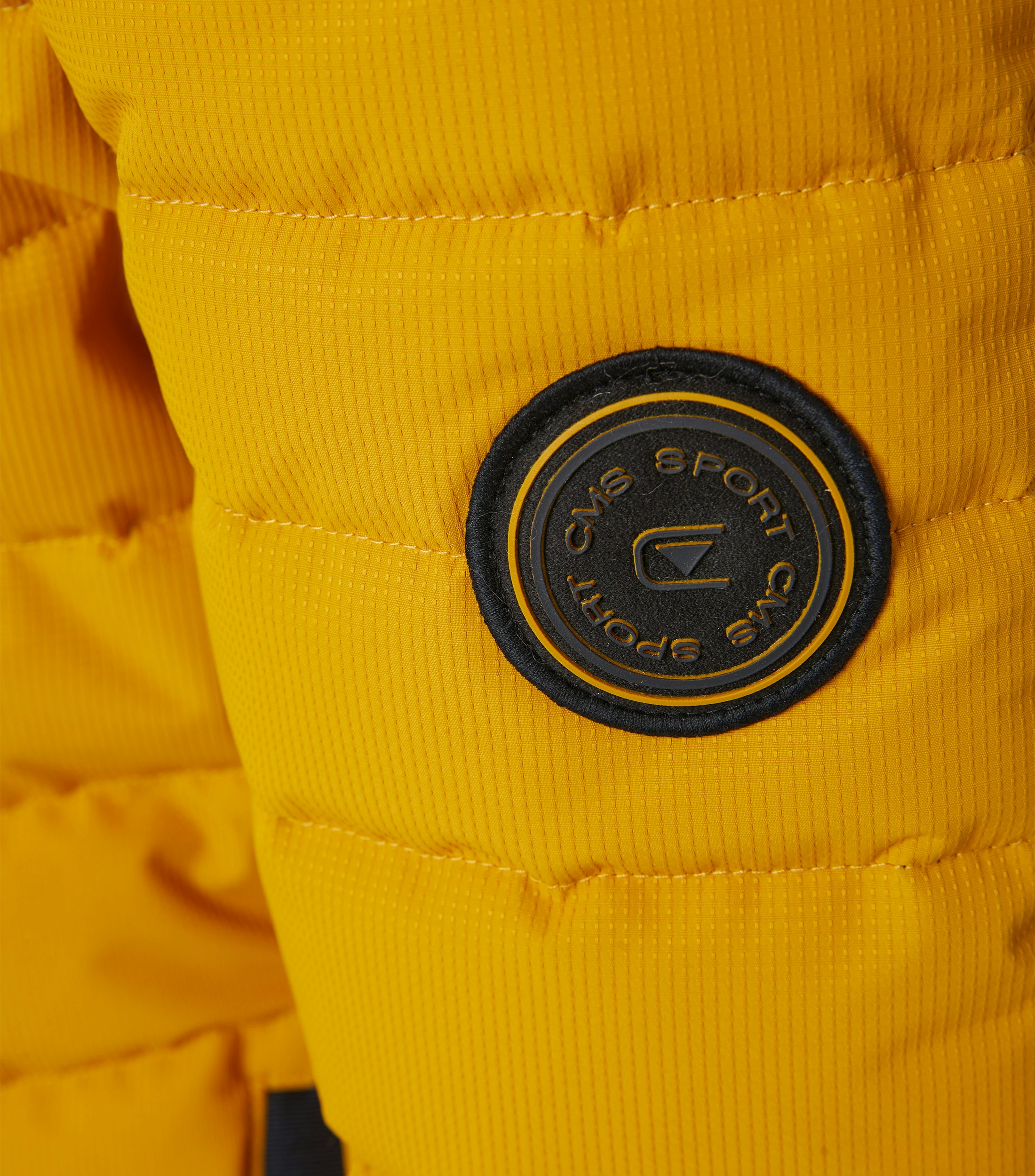 Das Model trägt eine Jacke im uni Muster in der Farbe Senfgelb