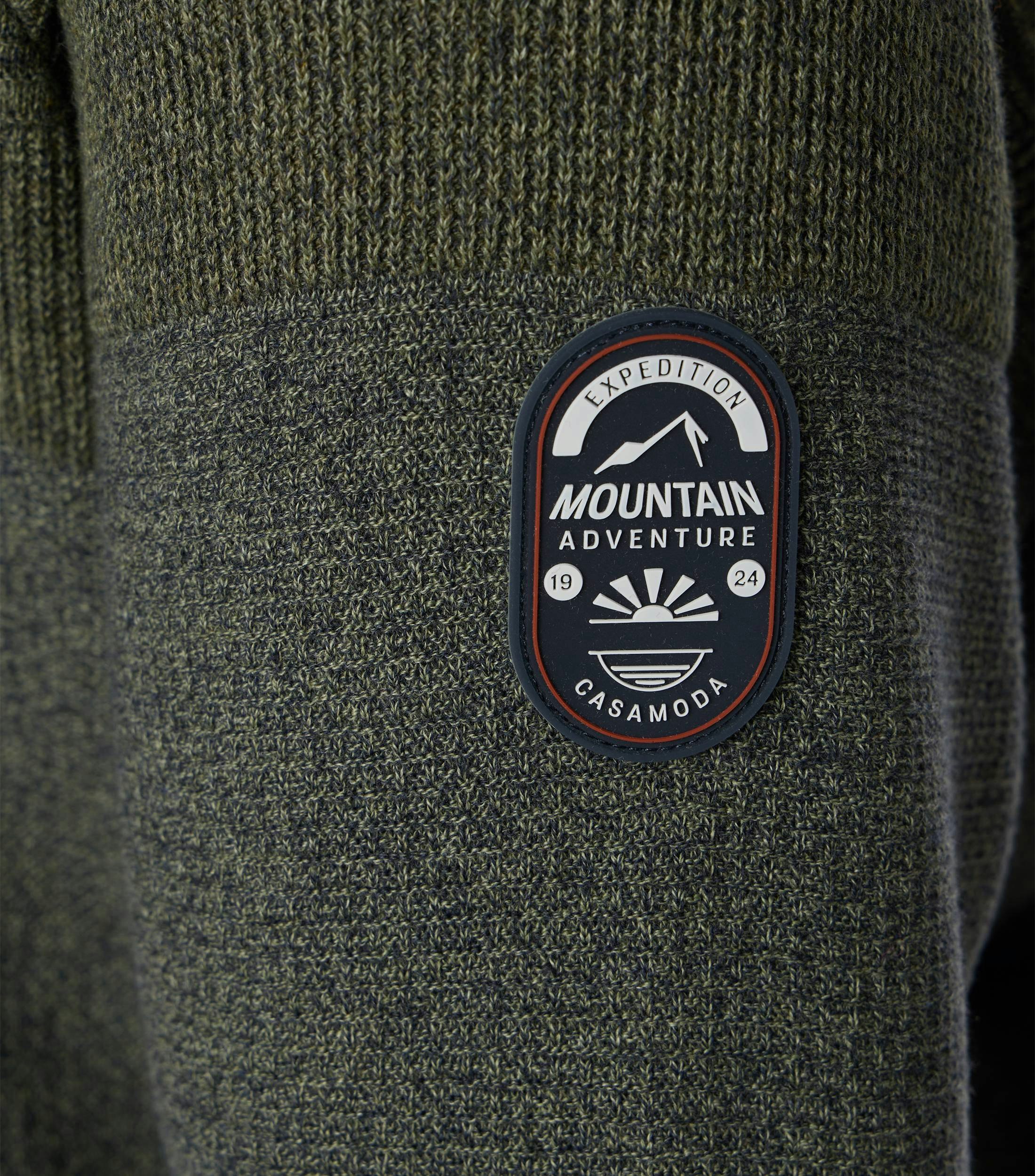 Das Model trägt ein Pullover im uni Muster in der Farbe Dunkelgrün