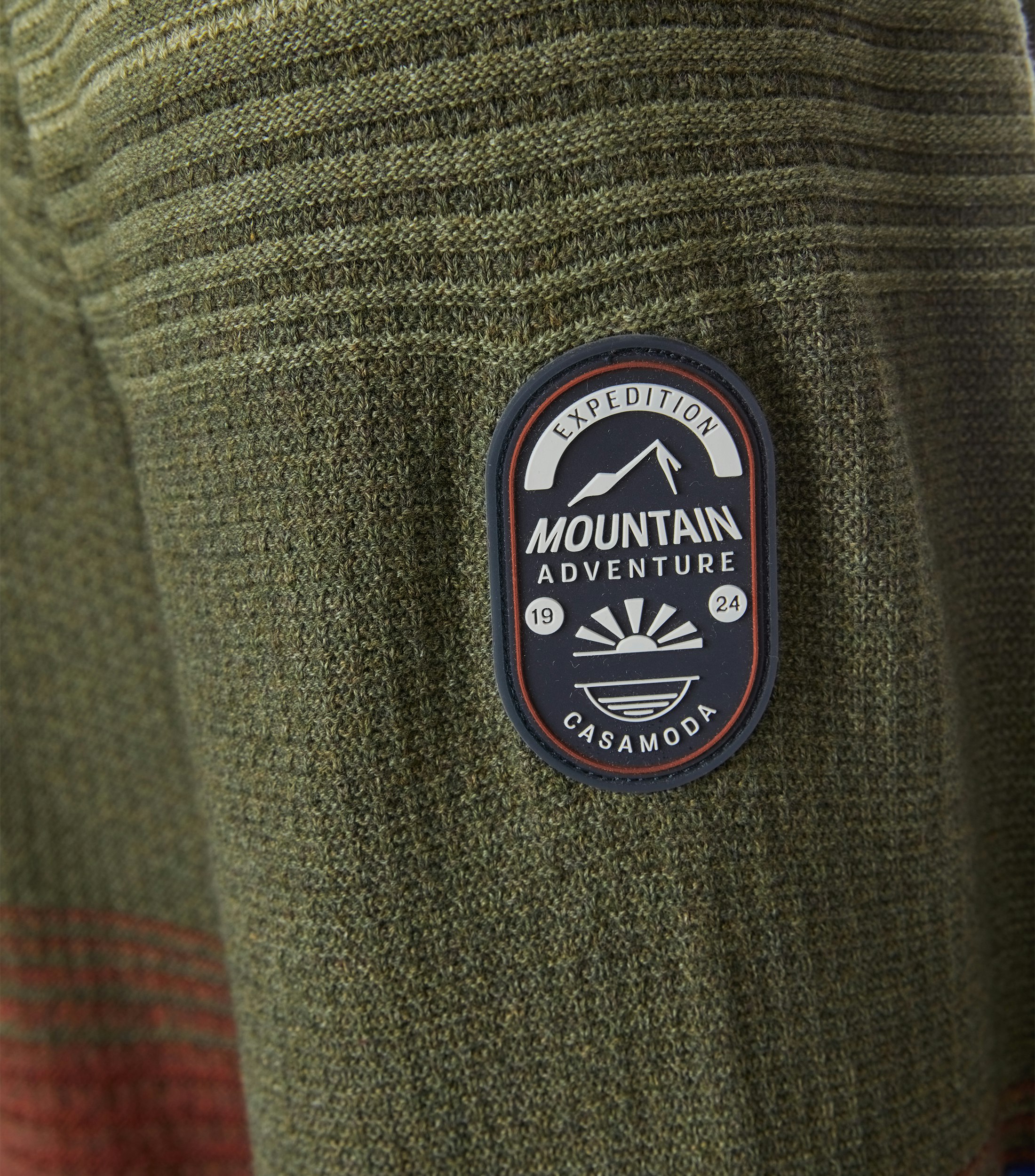 Das Model trägt ein Pullover im gestreift Muster in der Farbe Dunkelgrün