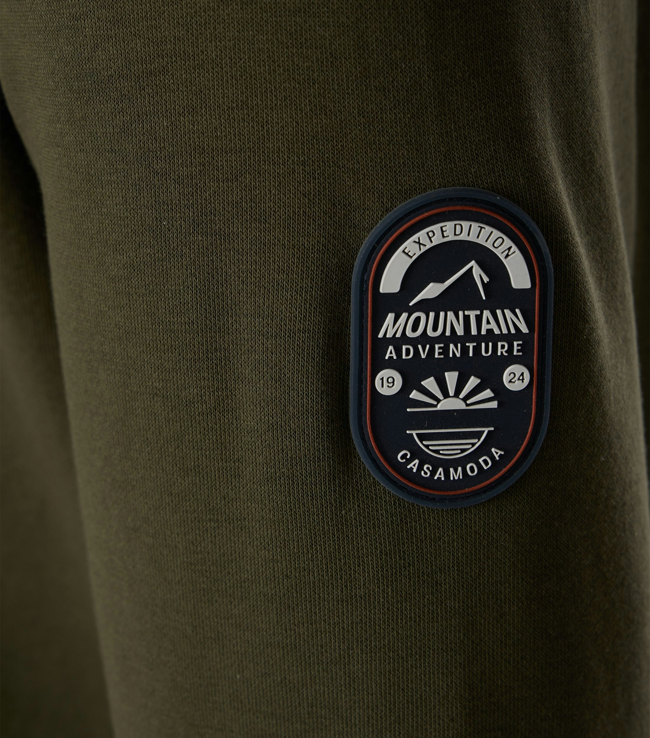 Das Model trägt ein Sweatshirt im uni Muster in der Farbe Dunkelgrün