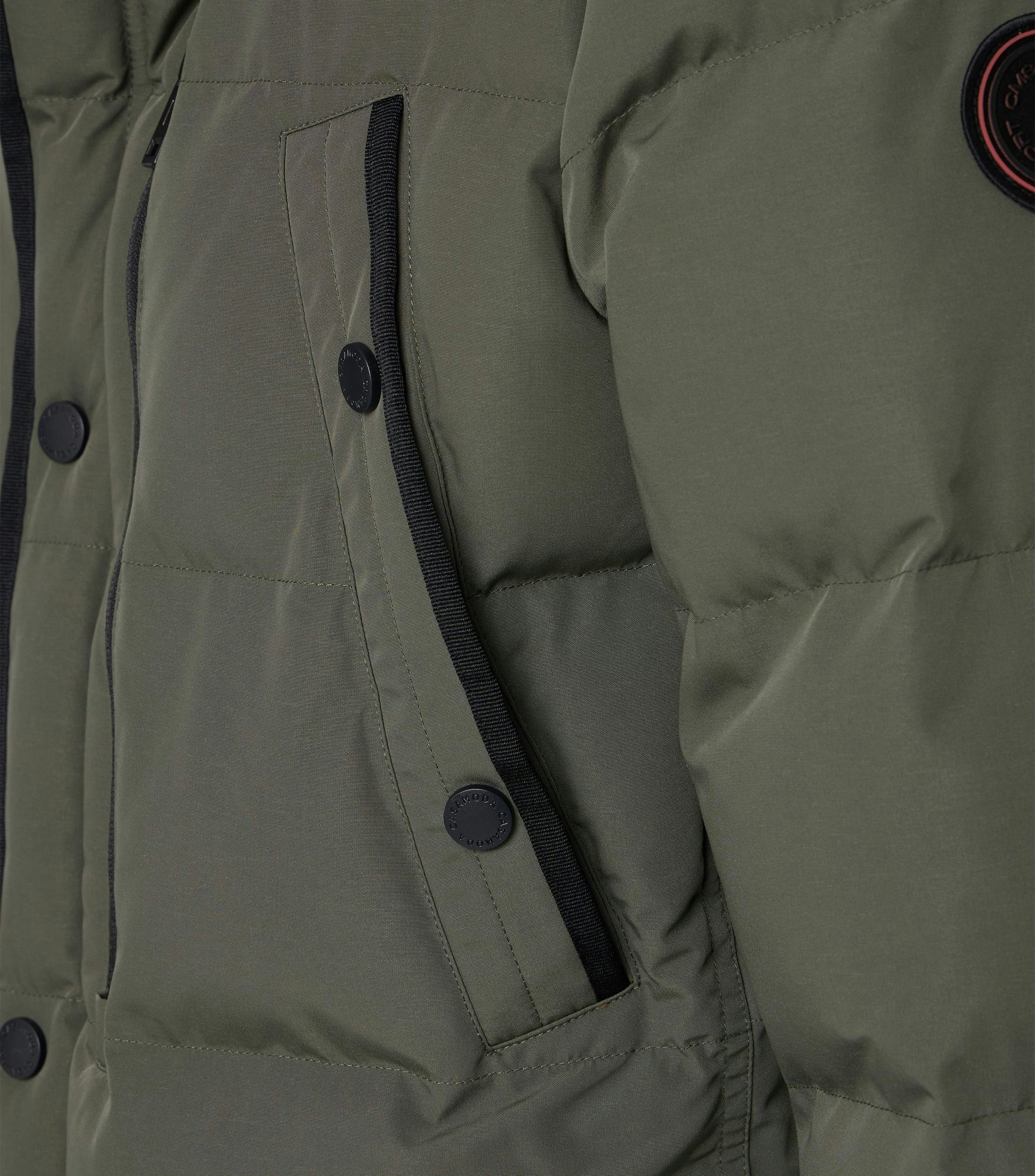 Das Model trägt eine Jacke im uni Muster in der Farbe Grün