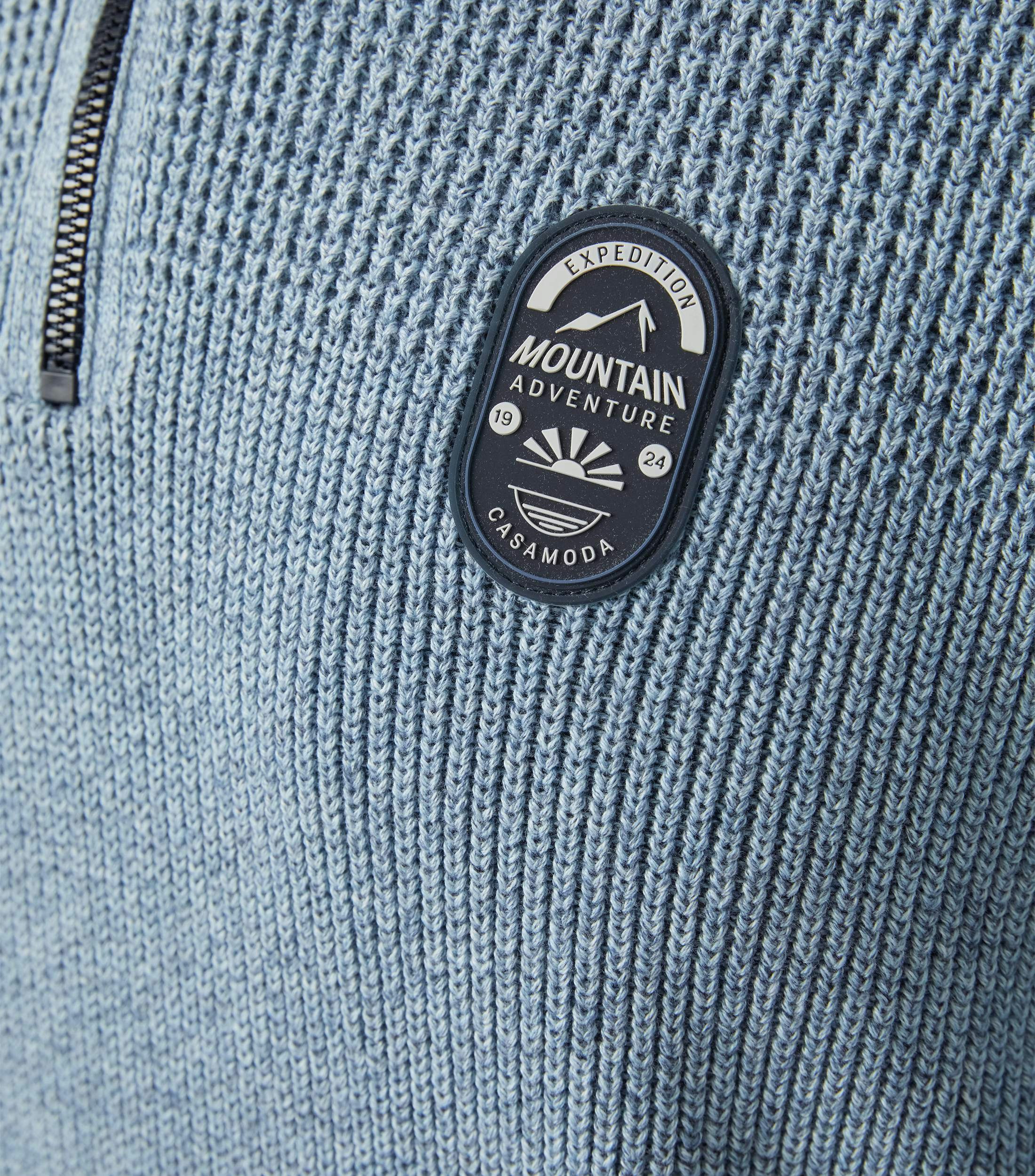 Das Model trägt ein Pullover im uni Muster in der Farbe Hellblau