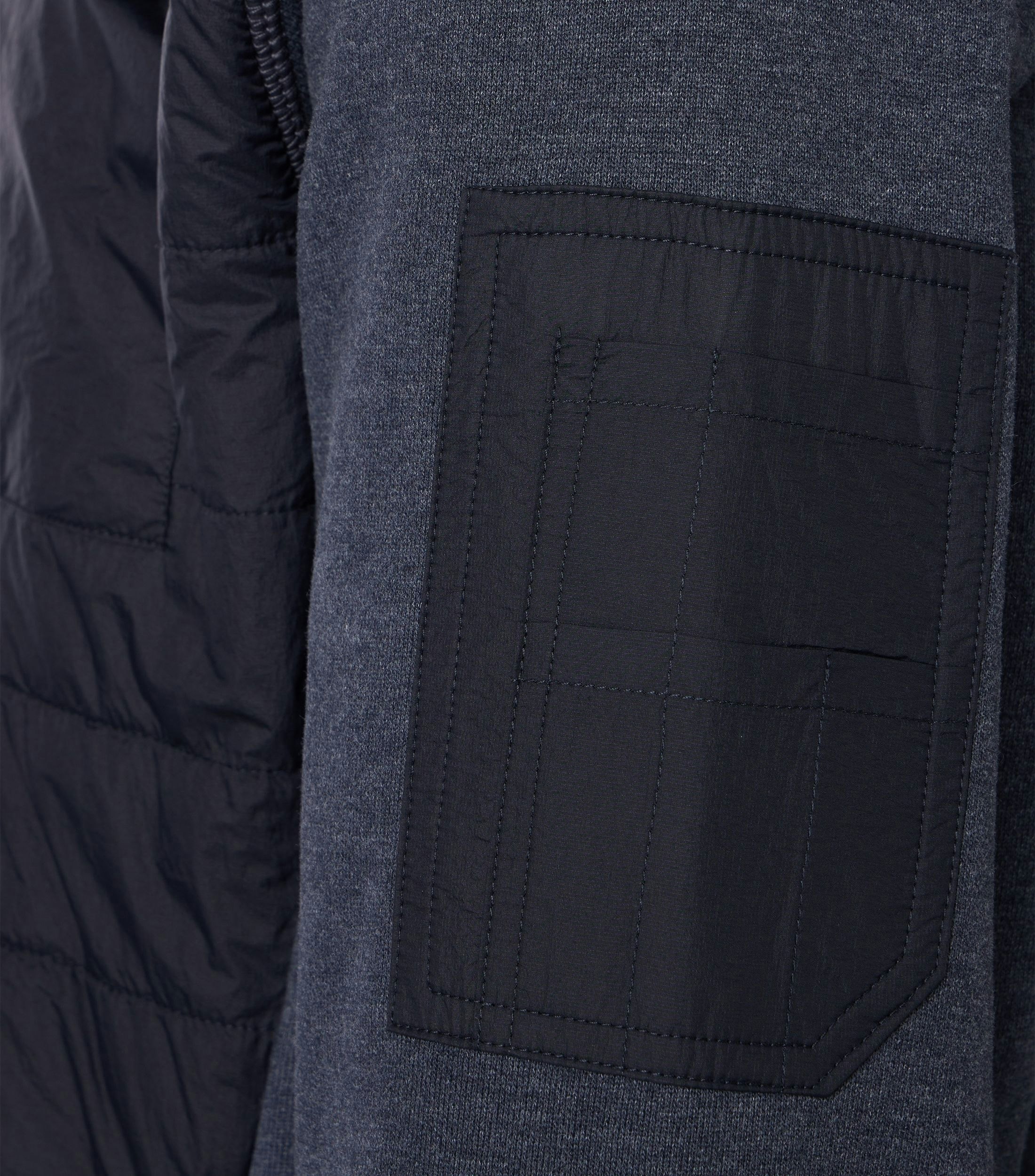 Das Model trägt eine Sweatjacke im uni Muster in der Farbe Blau