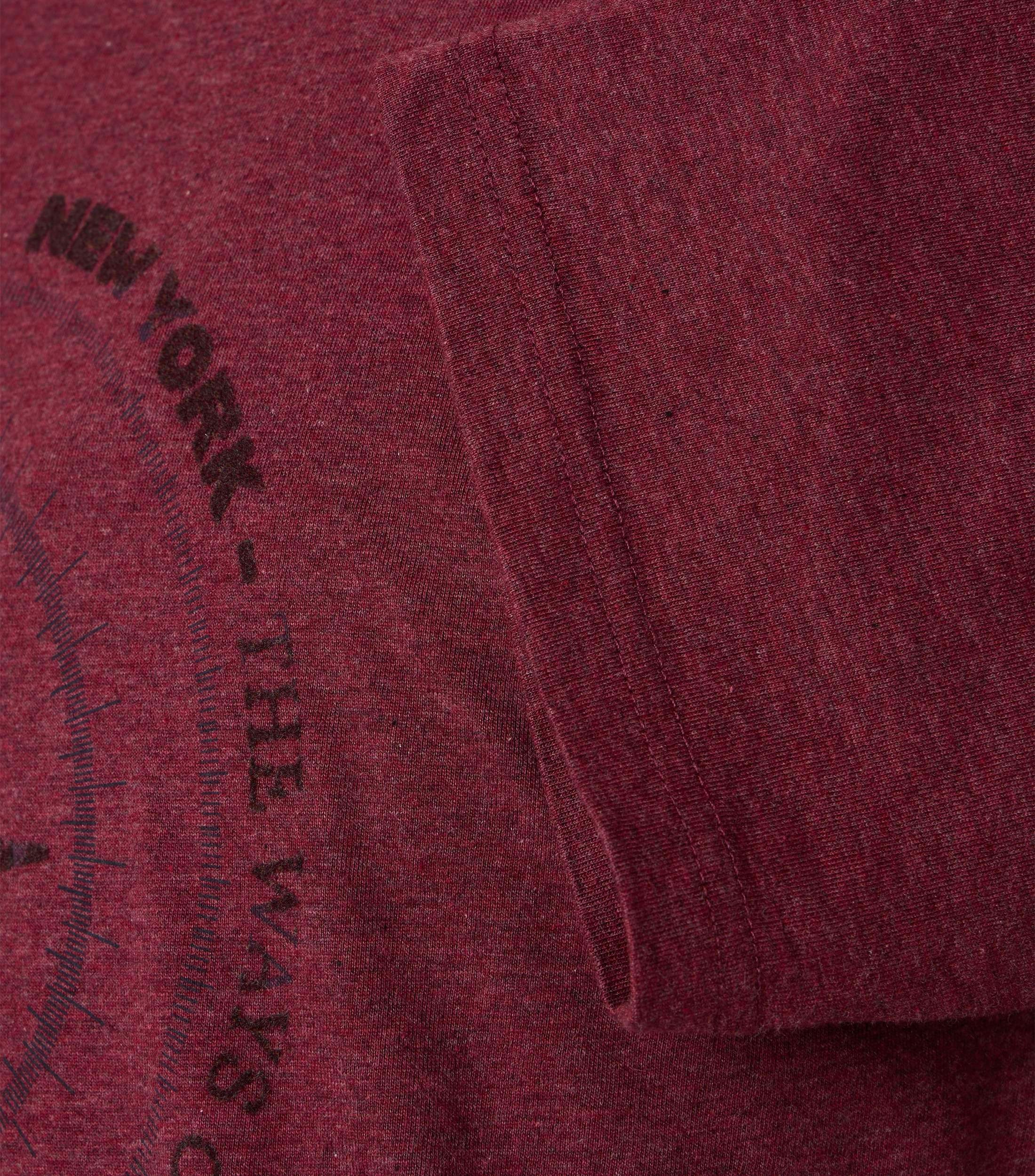 Das Model trägt ein TShirt im uni Muster in der Farbe Rot