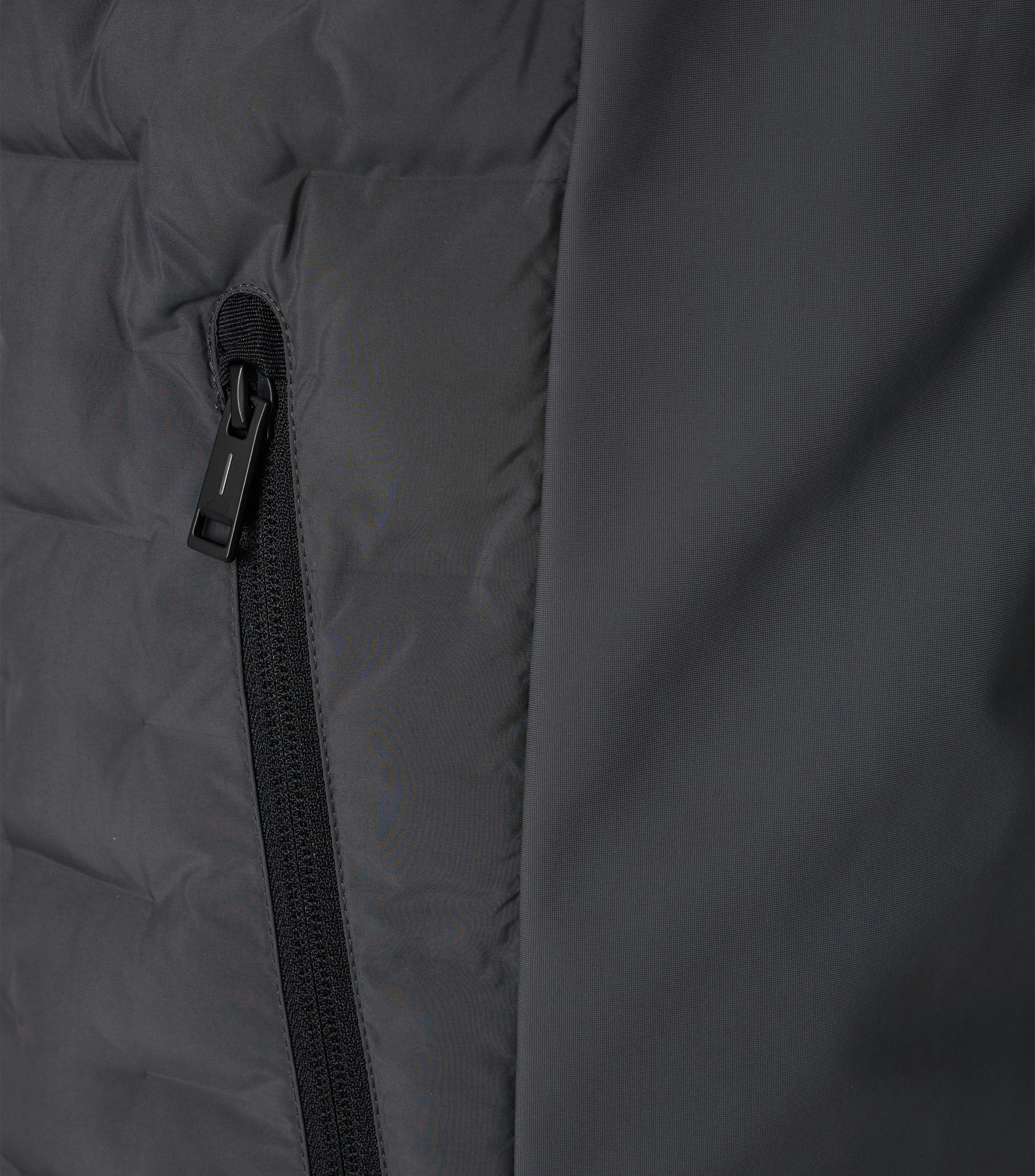 Das Model trägt eine Weste im uni Muster in der Farbe Grau