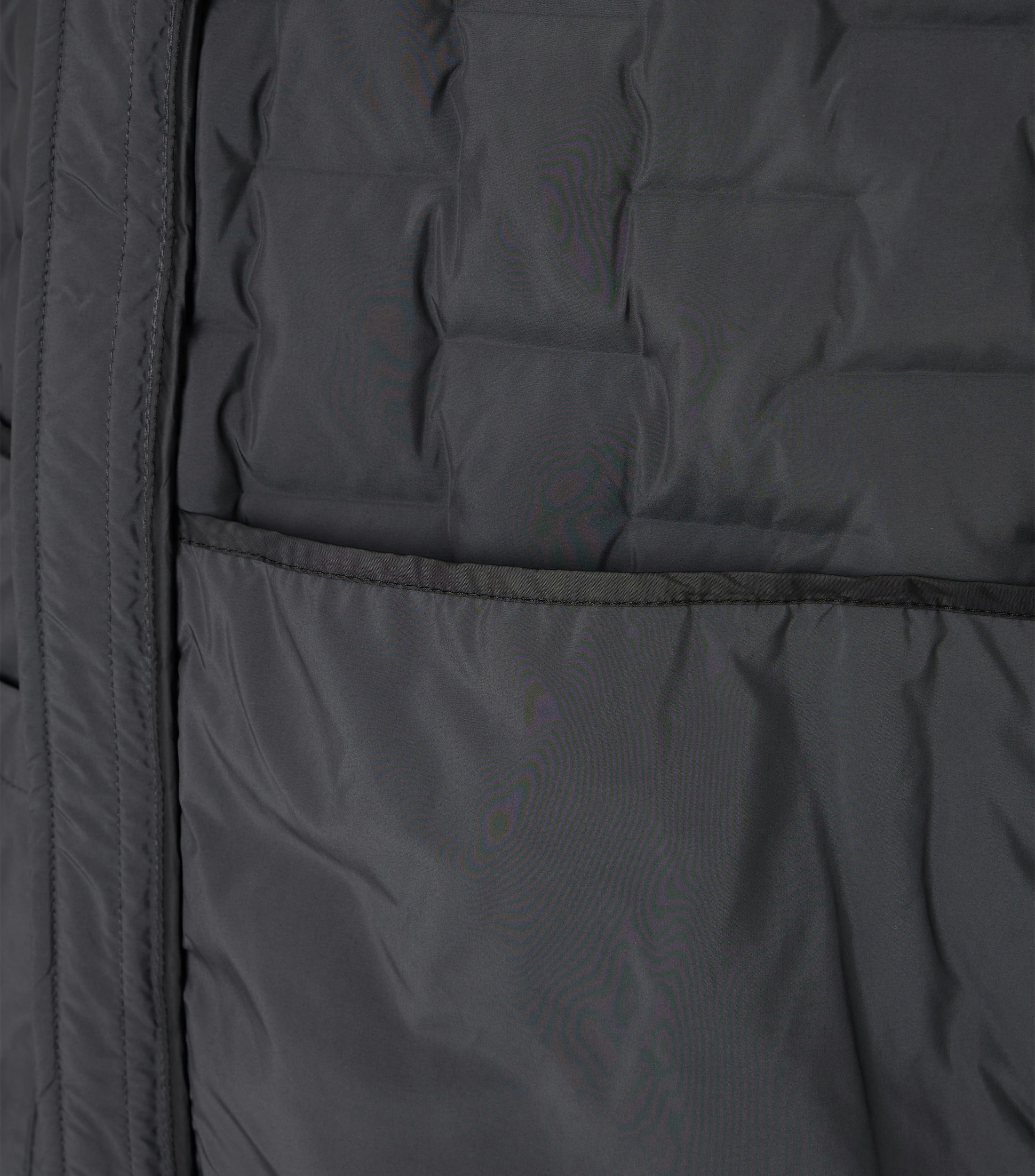 Das Model trägt eine Weste im uni Muster in der Farbe Grau