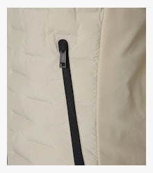 Das Model trägt eine Weste im uni Muster in der Farbe Weißbeige