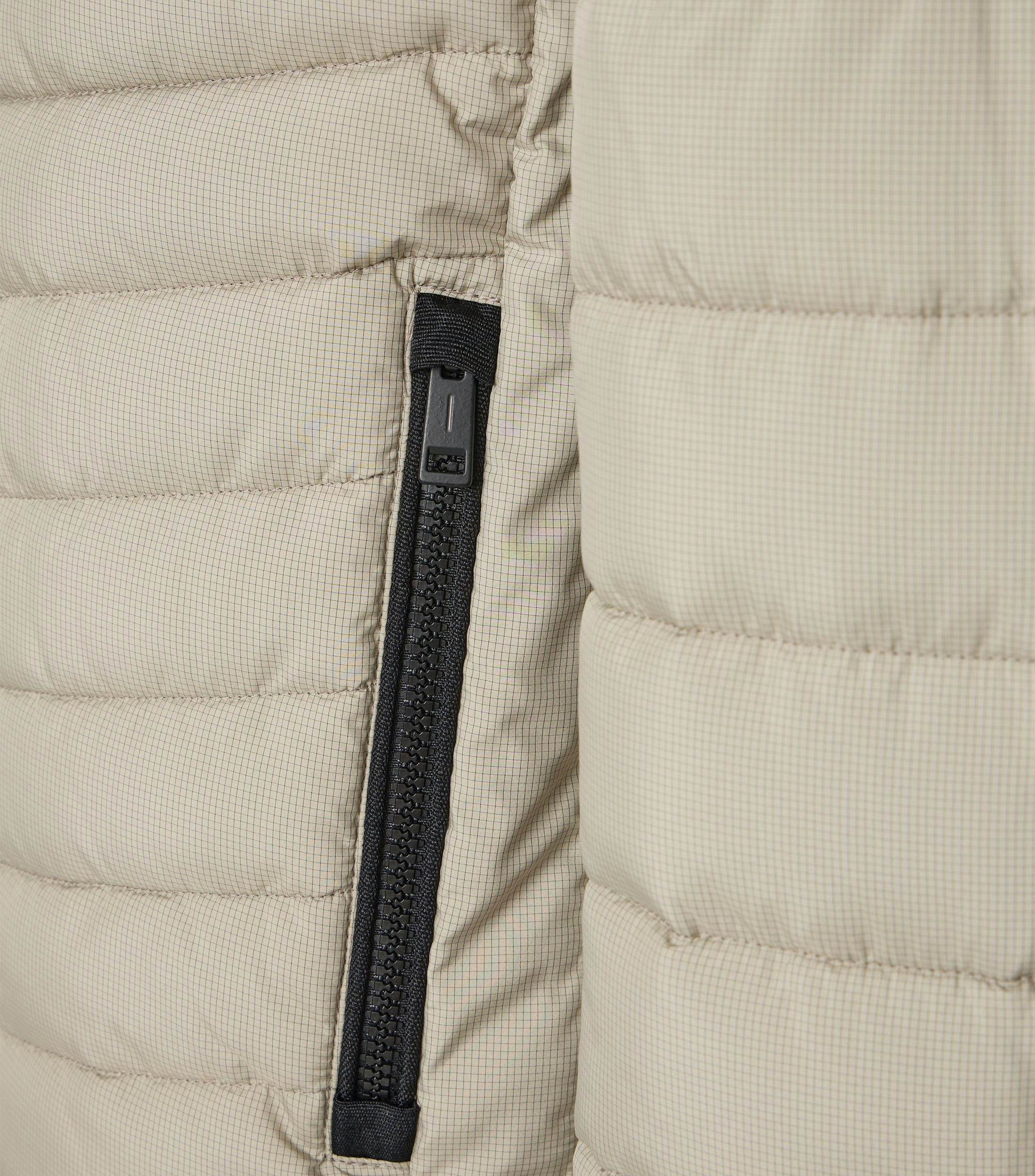 Das Model trägt eine Jacke im uni Muster in der Farbe Weißbeige