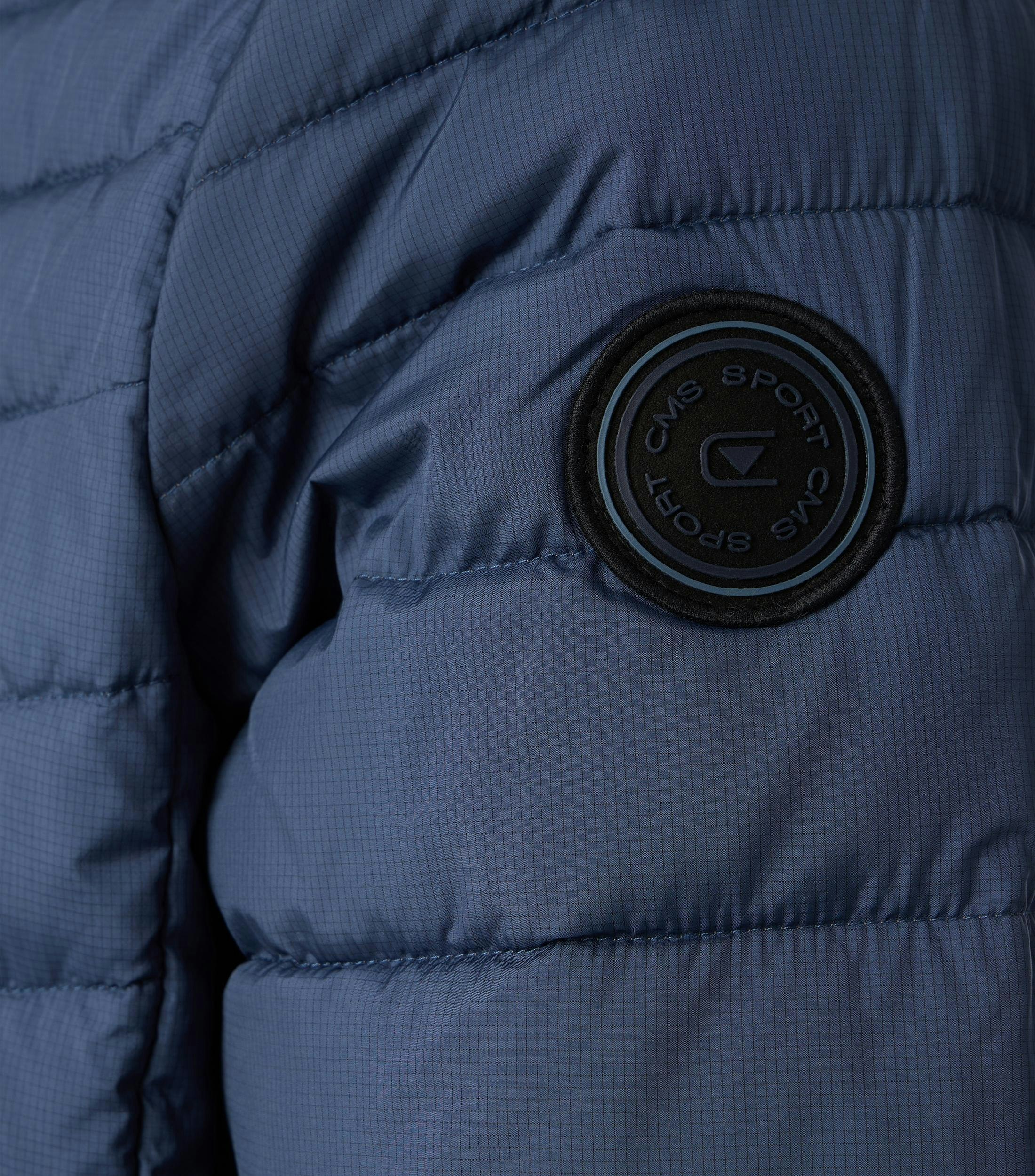 Das Model trägt eine Jacke im uni Muster in der Farbe Blau