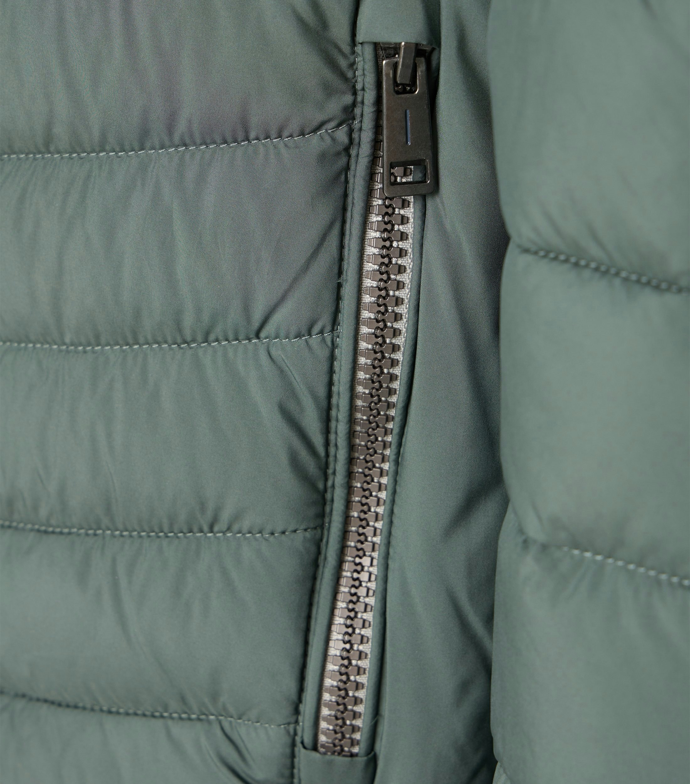 Das Model trägt eine Jacke im uni Muster in der Farbe Grün