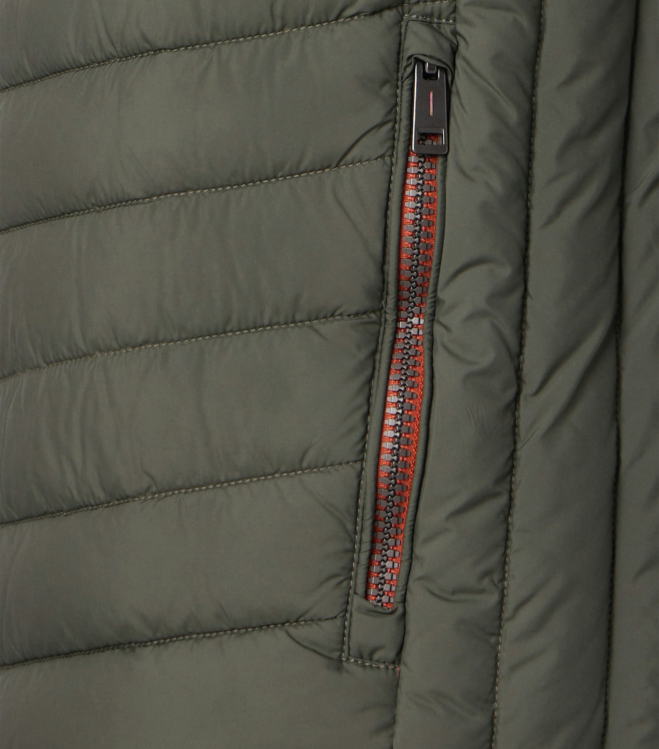 Das Model trägt eine Weste im uni Muster in der Farbe Grün