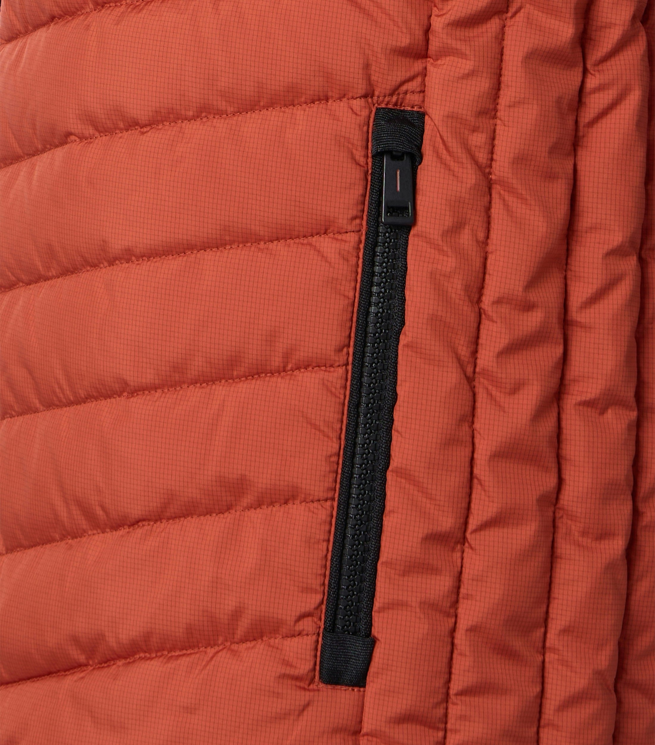 Das Model trägt eine Weste im uni Muster in der Farbe Orange