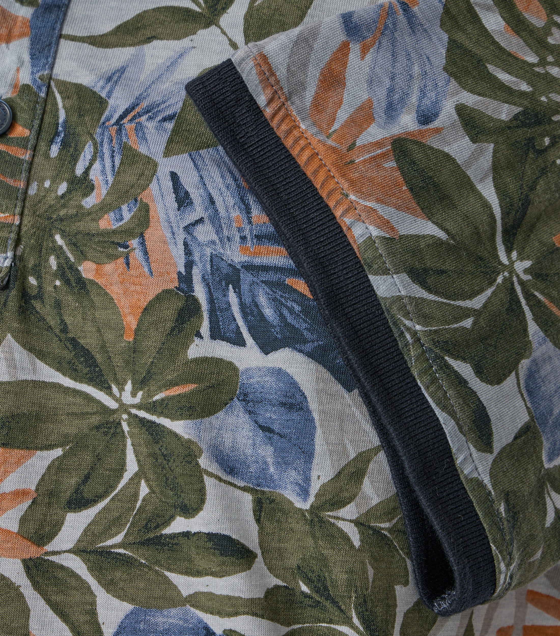 Das Model trägt ein PoloShirt im Print Muster in der Farbe Blau