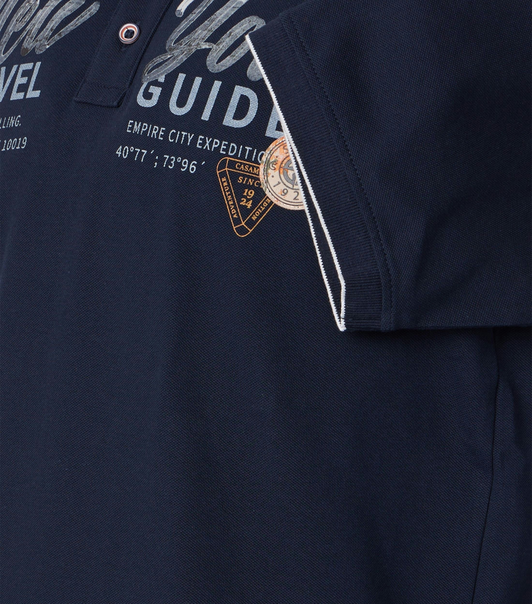 Das Model trägt ein PoloShirt im uni Muster in der Farbe Blau