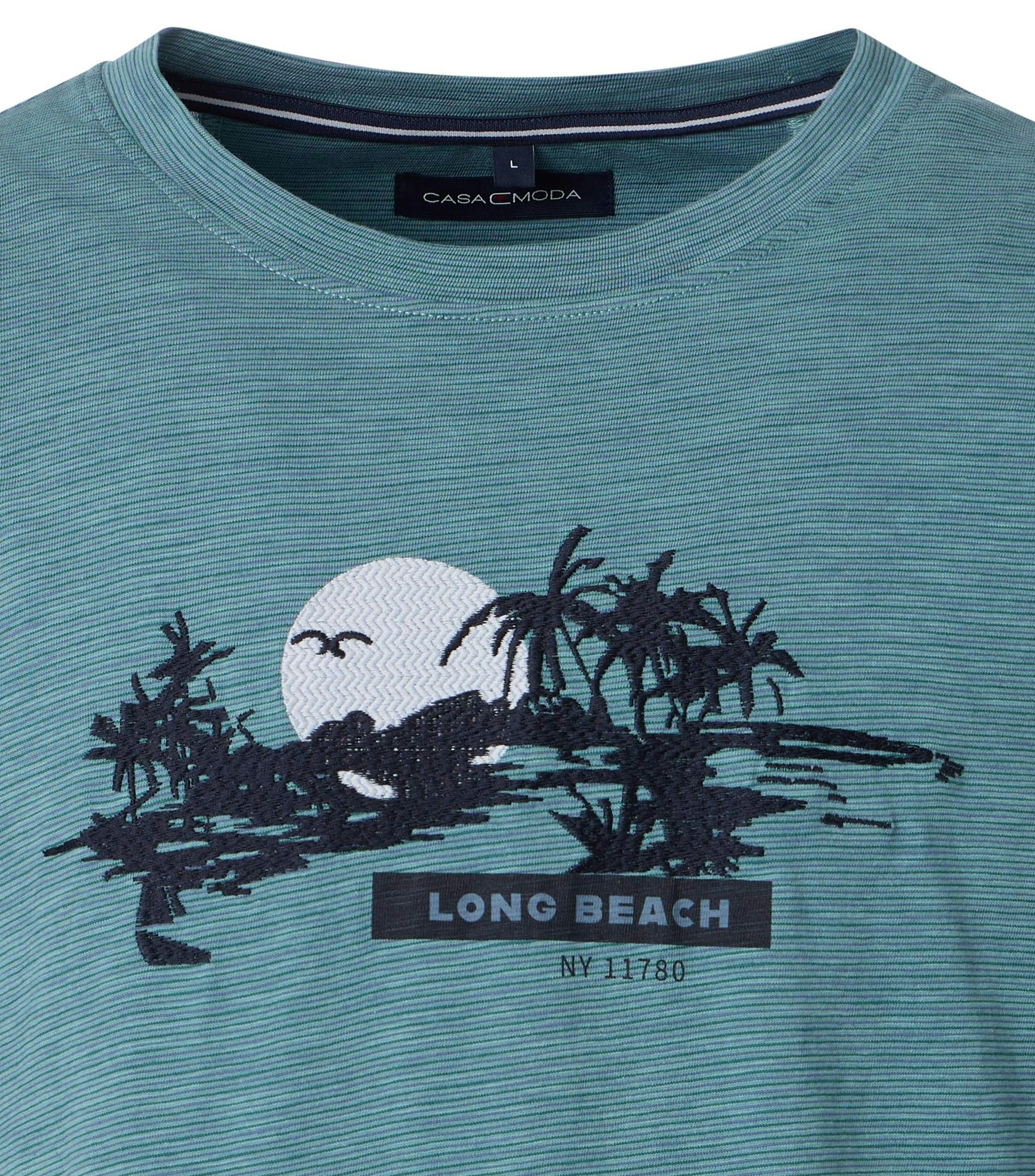 Das Model trägt ein TShirt im Print Muster in der Farbe Türkis