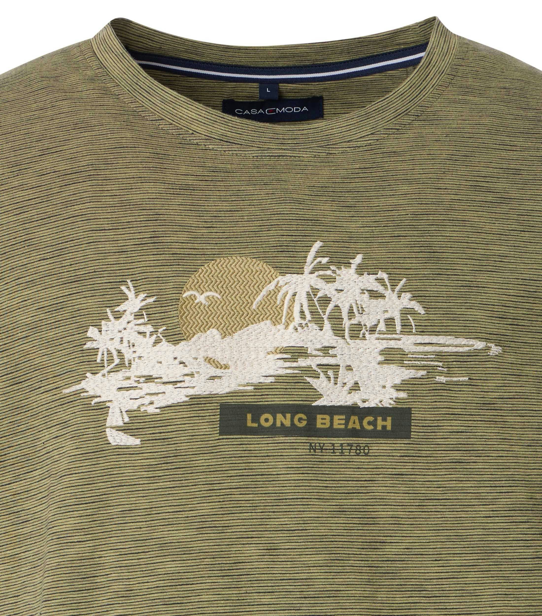 Das Model trägt ein TShirt im Print Muster in der Farbe Grün