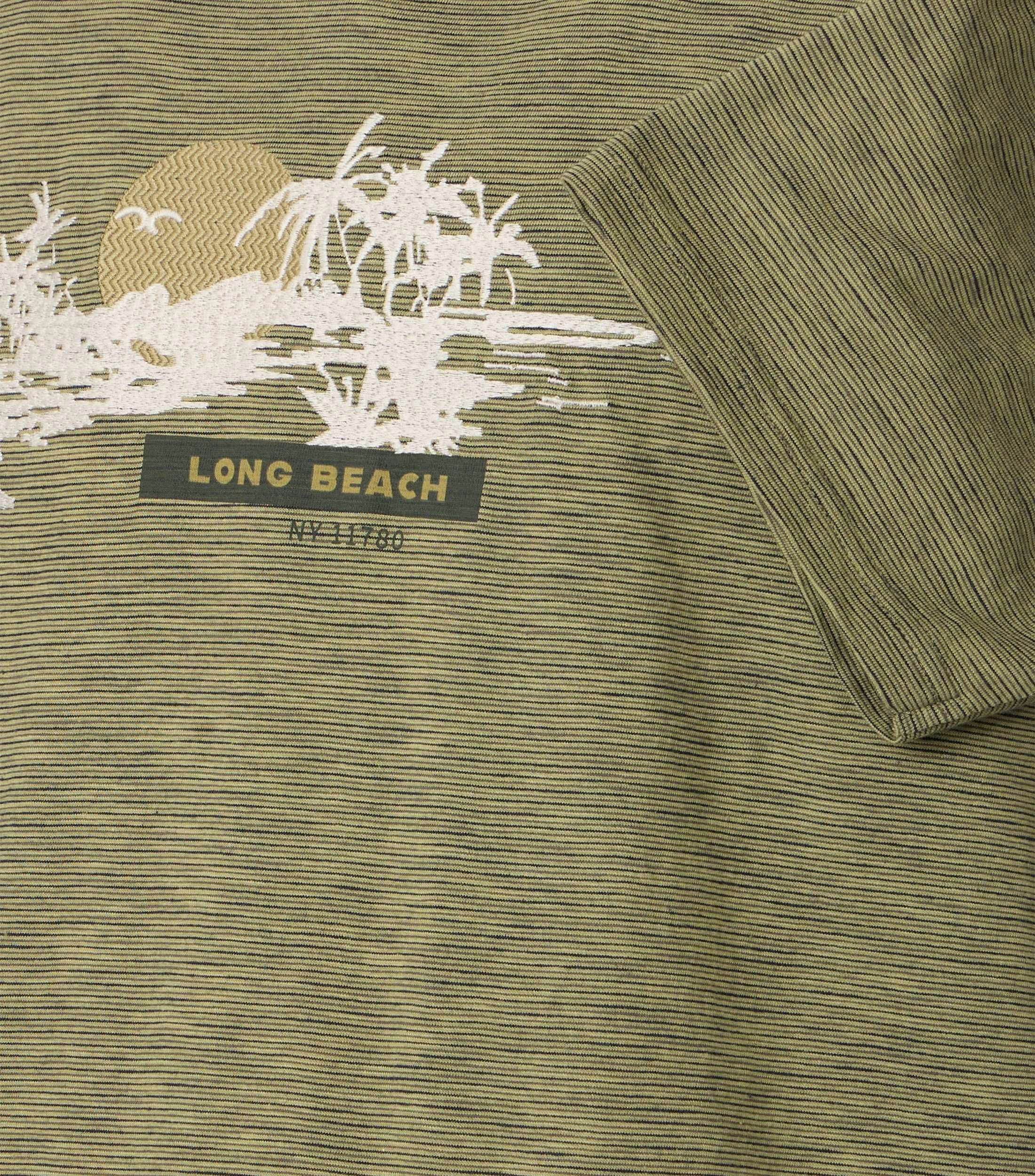 Das Model trägt ein TShirt im Print Muster in der Farbe Grün