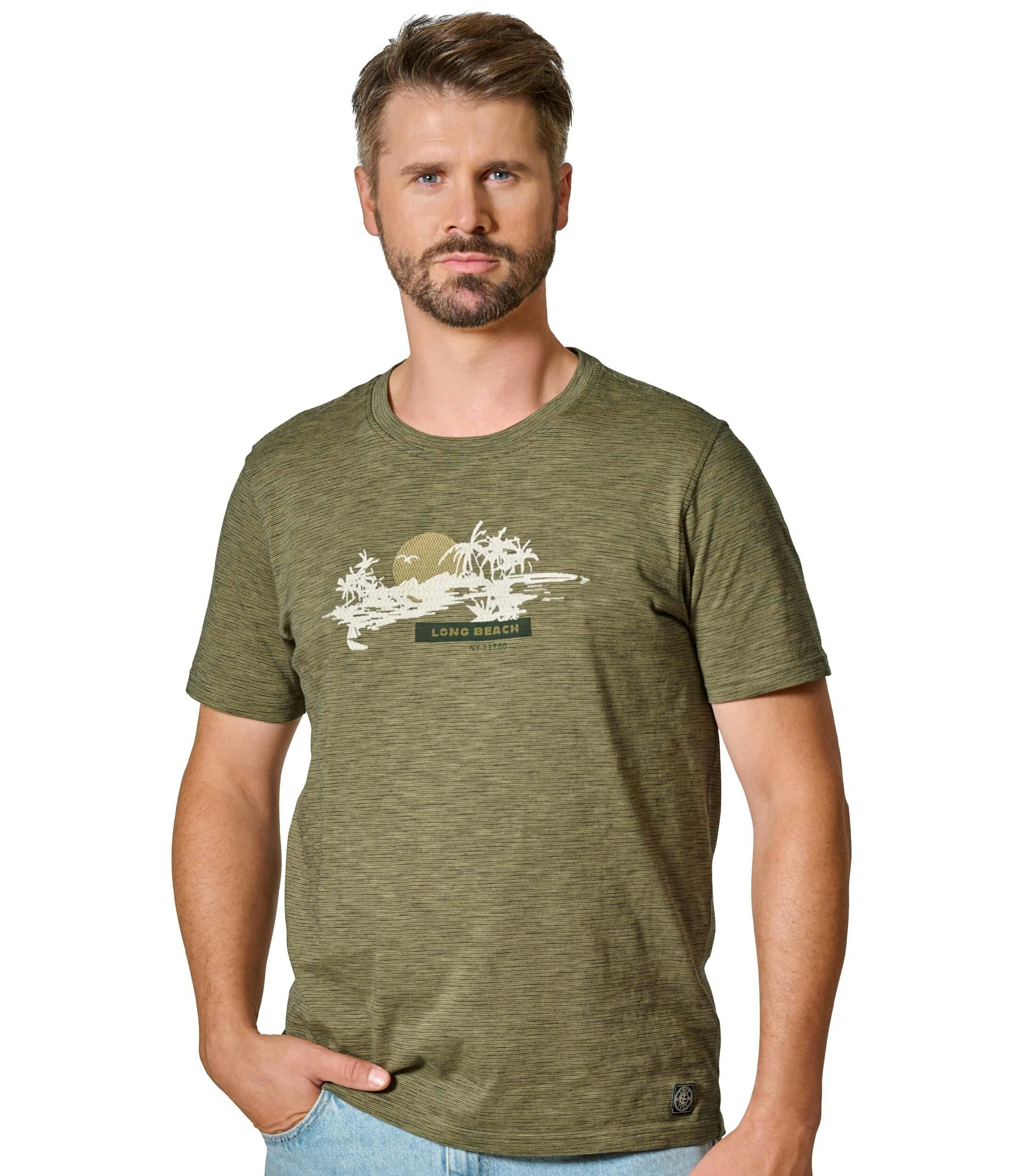 Das Model trägt ein TShirt im Print Muster in der Farbe Grün