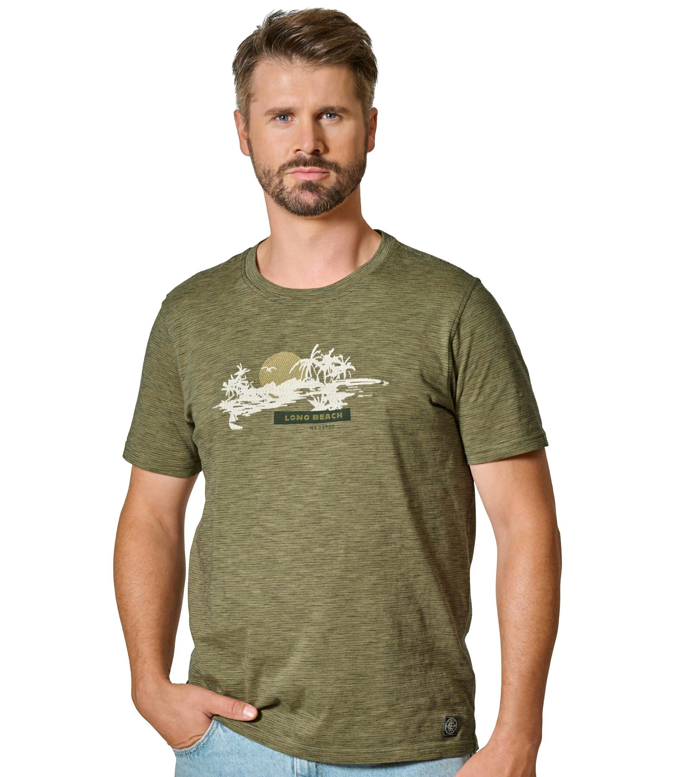 Das Model trägt ein TShirt im Print Muster in der Farbe Grün