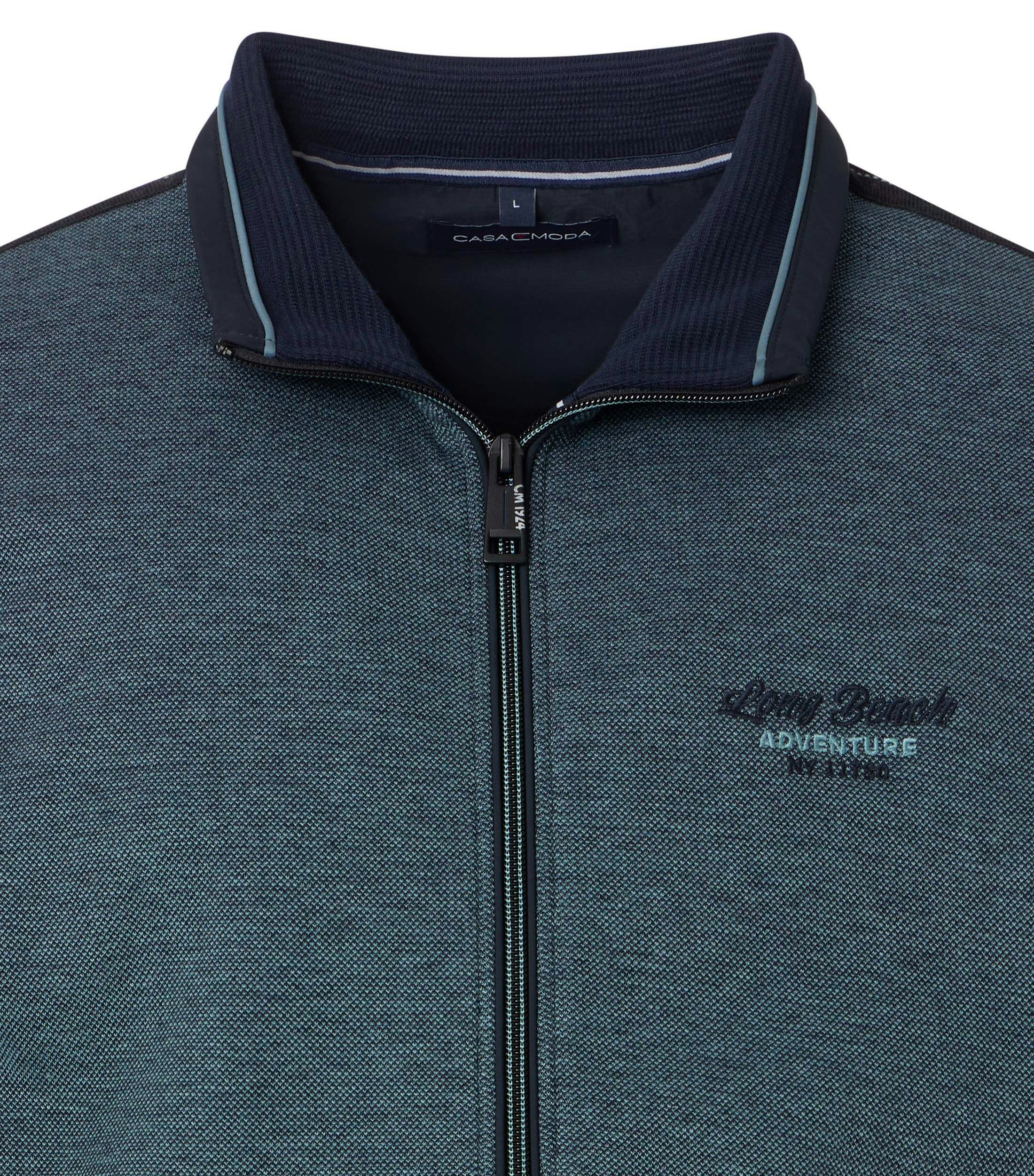 Das Model trägt eine Sweatjacke im uni Muster in der Farbe Türkis