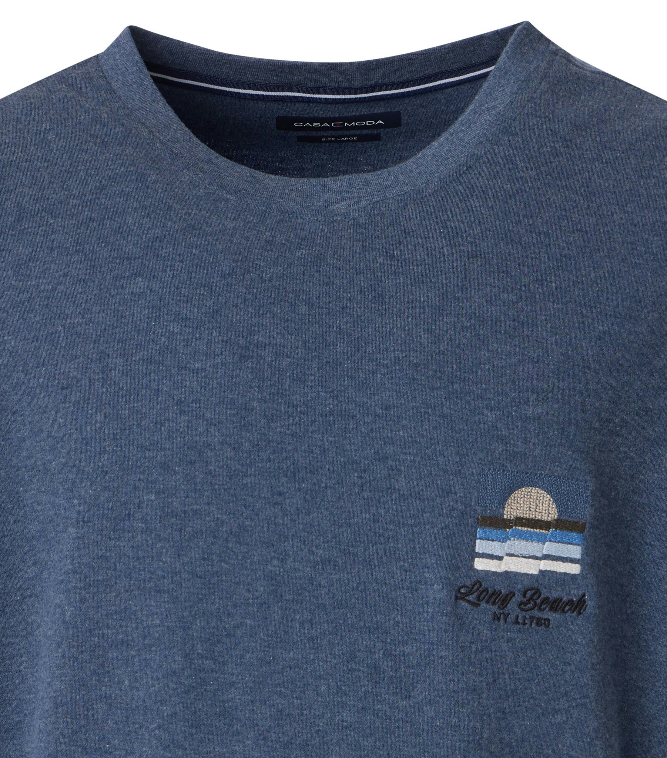 Das Model trägt ein TShirt im uni Muster in der Farbe Blau