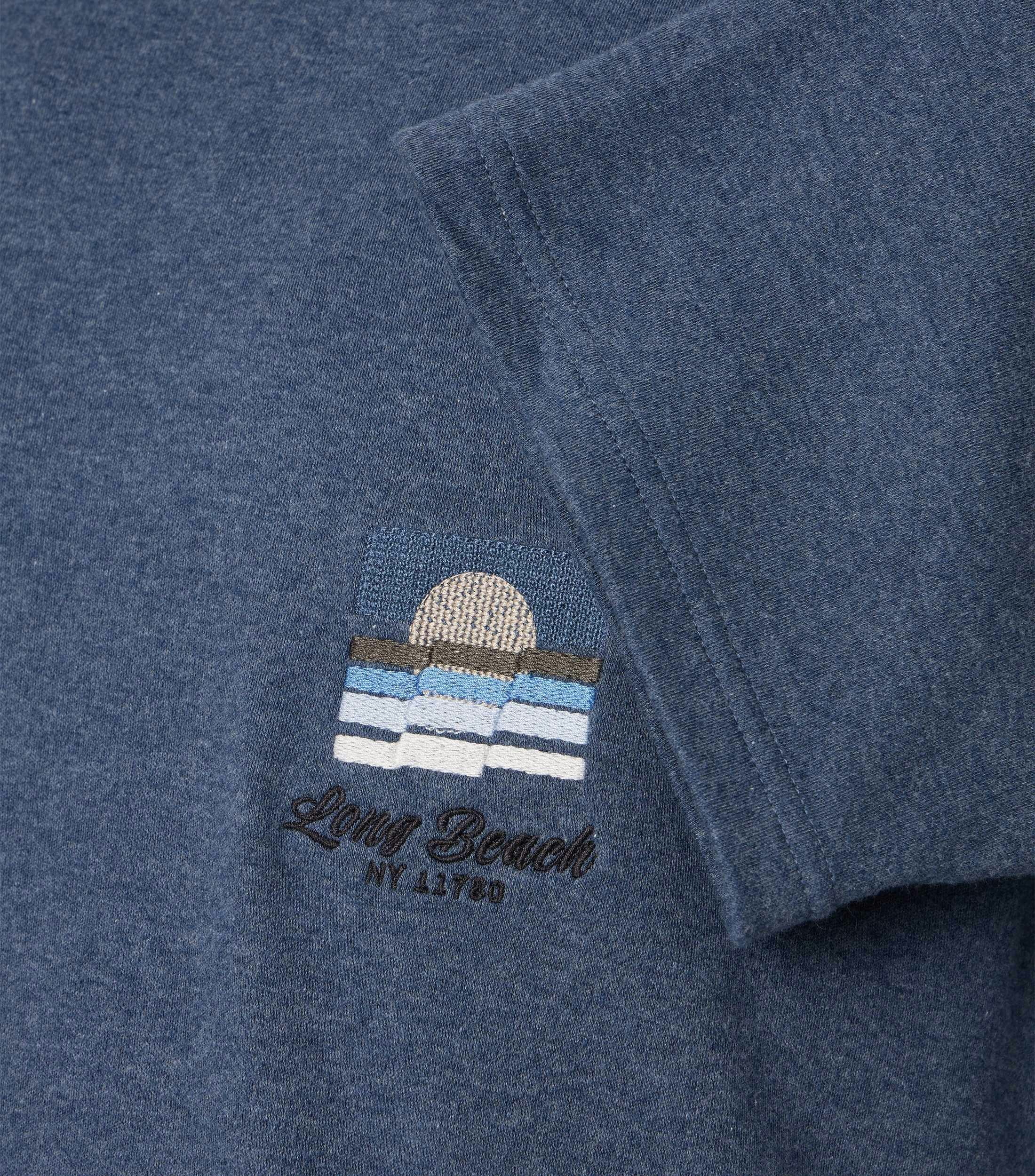 Das Model trägt ein TShirt im uni Muster in der Farbe Blau