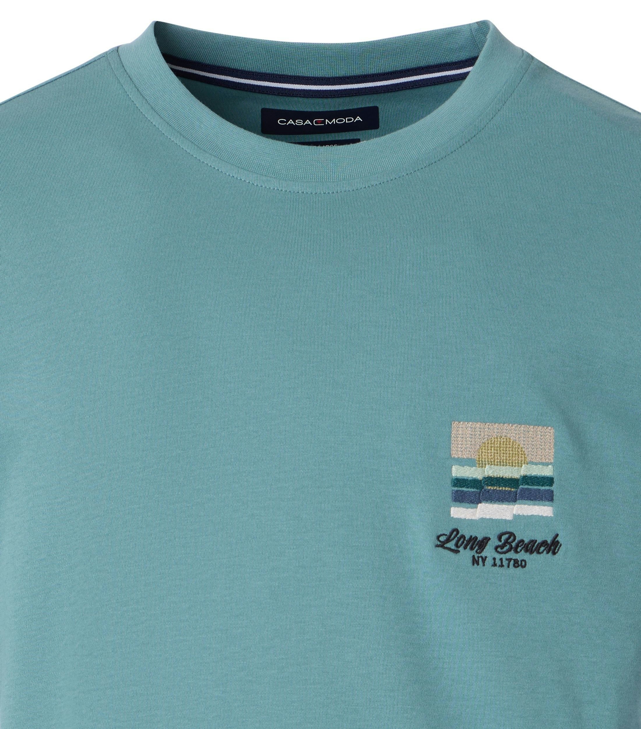 Das Model trägt ein TShirt im uni Muster in der Farbe Türkis