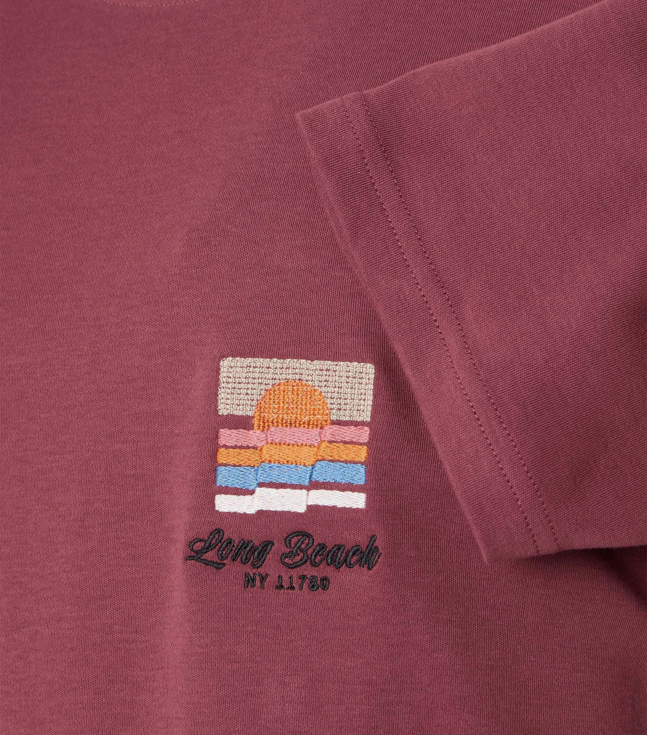 Das Model trägt ein TShirt im uni Muster in der Farbe Rot