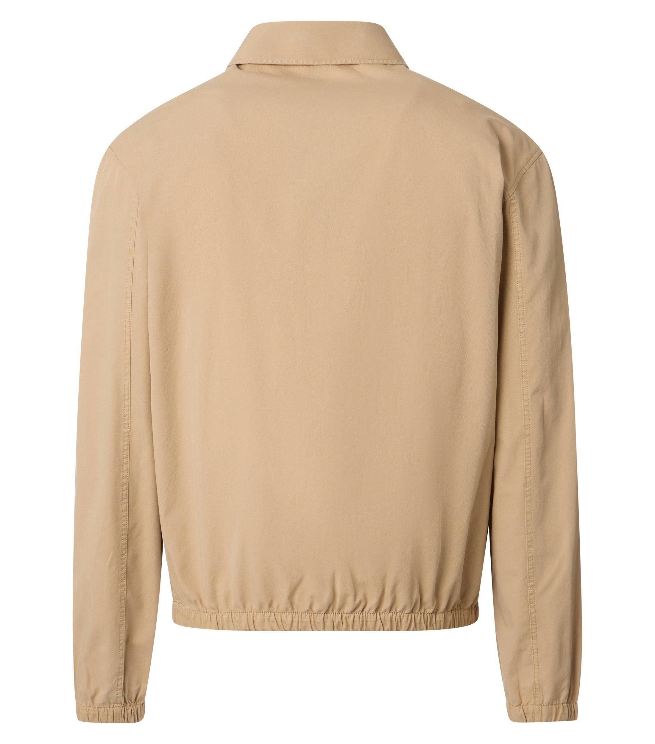 Das Model trägt eine Jacke im uni Muster in der Farbe Beige