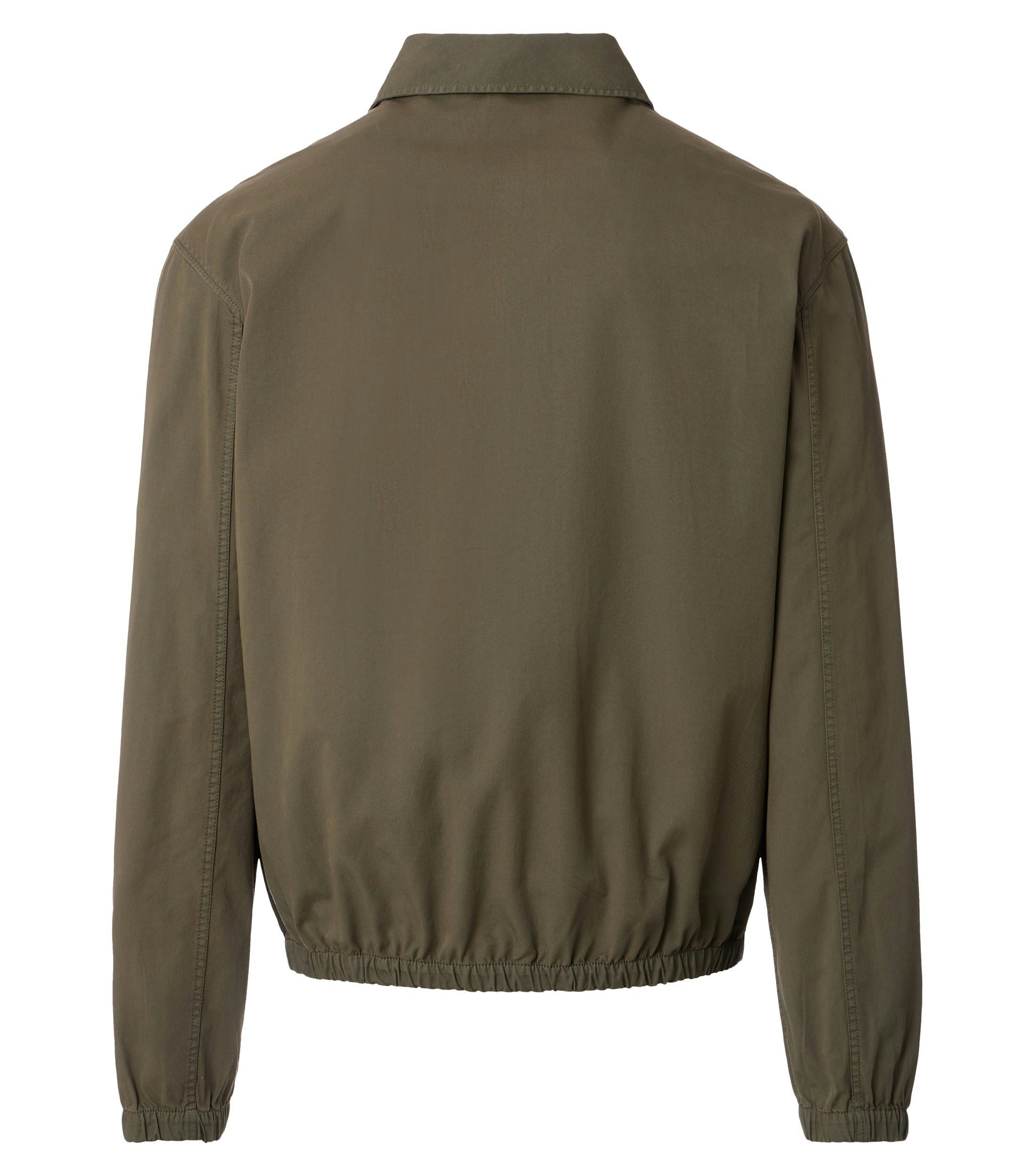 Das Model trägt eine Jacke im uni Muster in der Farbe Dunkelgrün