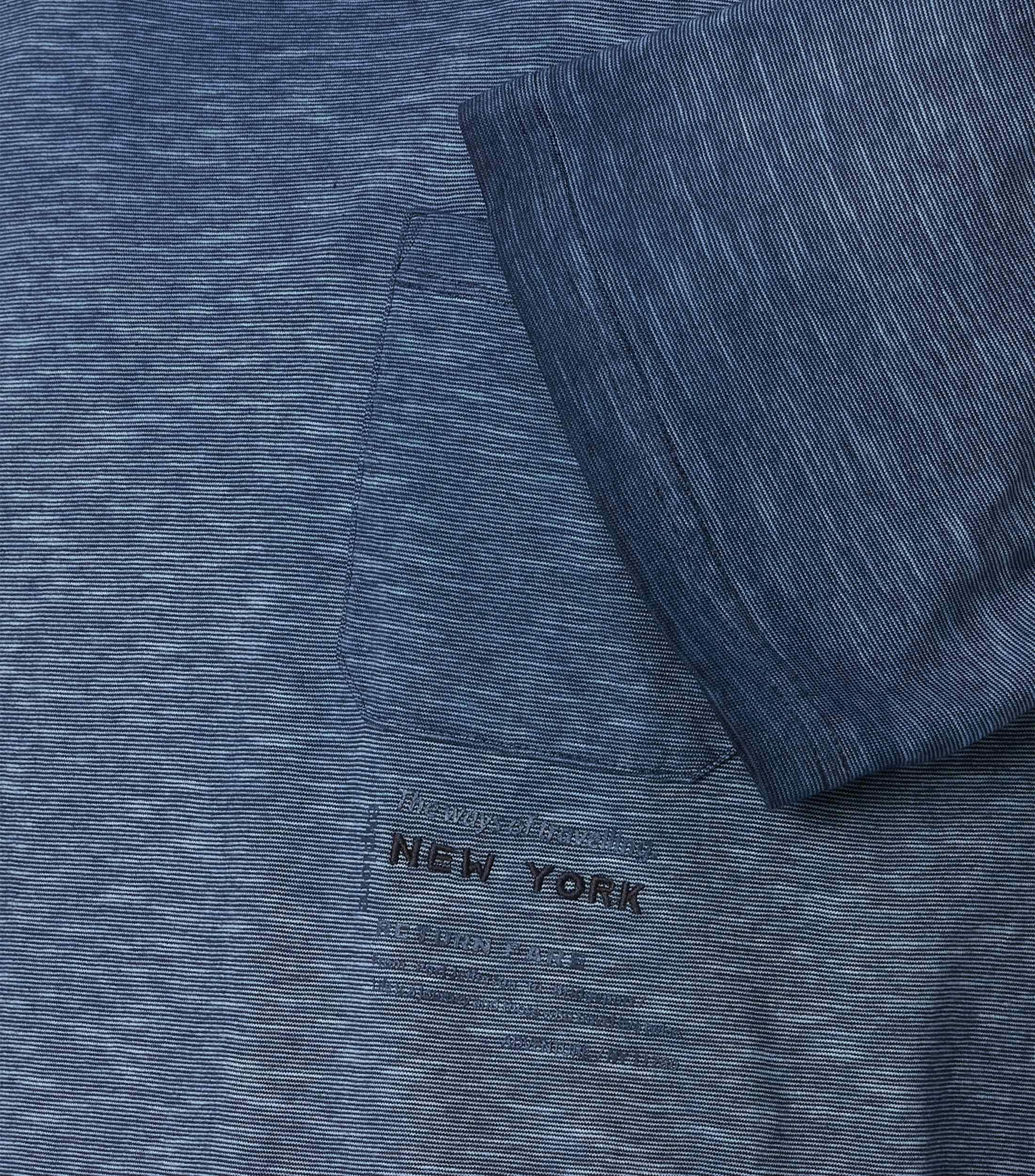 Das Model trägt ein TShirt im uni Muster in der Farbe Blau