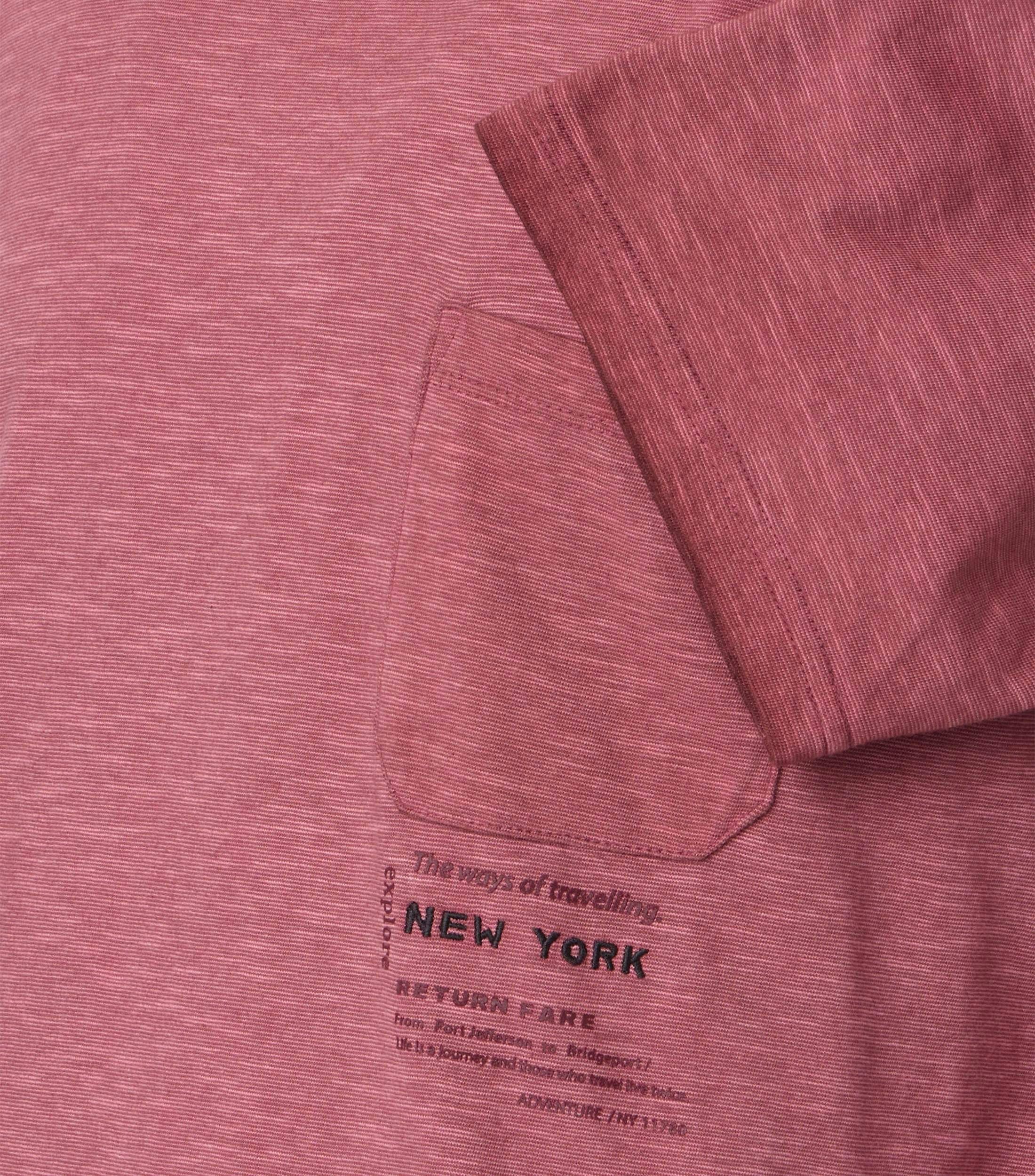 Das Model trägt ein TShirt im uni Muster in der Farbe Rotorange