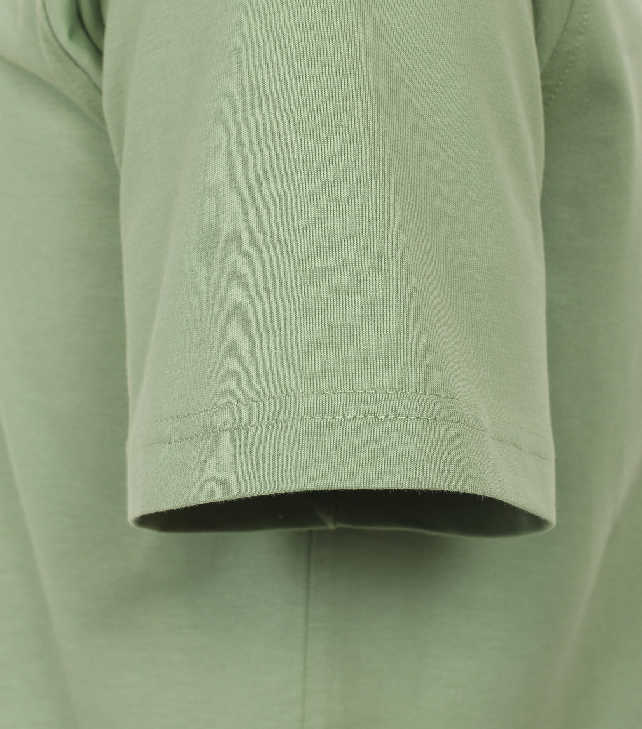 Das Model trägt ein TShirt im uni Muster in der Farbe Grün